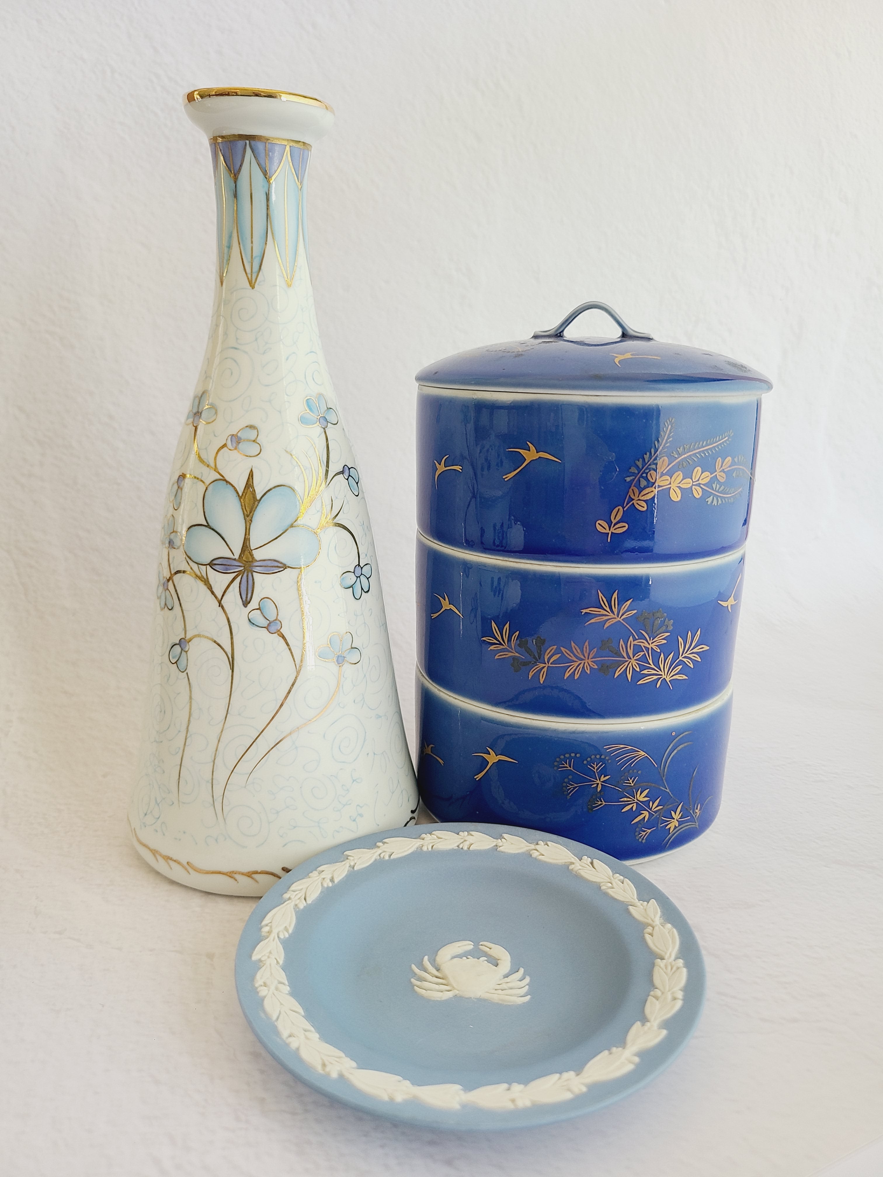 Vintage Fukagawa Seiji 3-Tier Stacking Bowl Set with Lid in lapis blue with gold accents displayed with other porcelain.