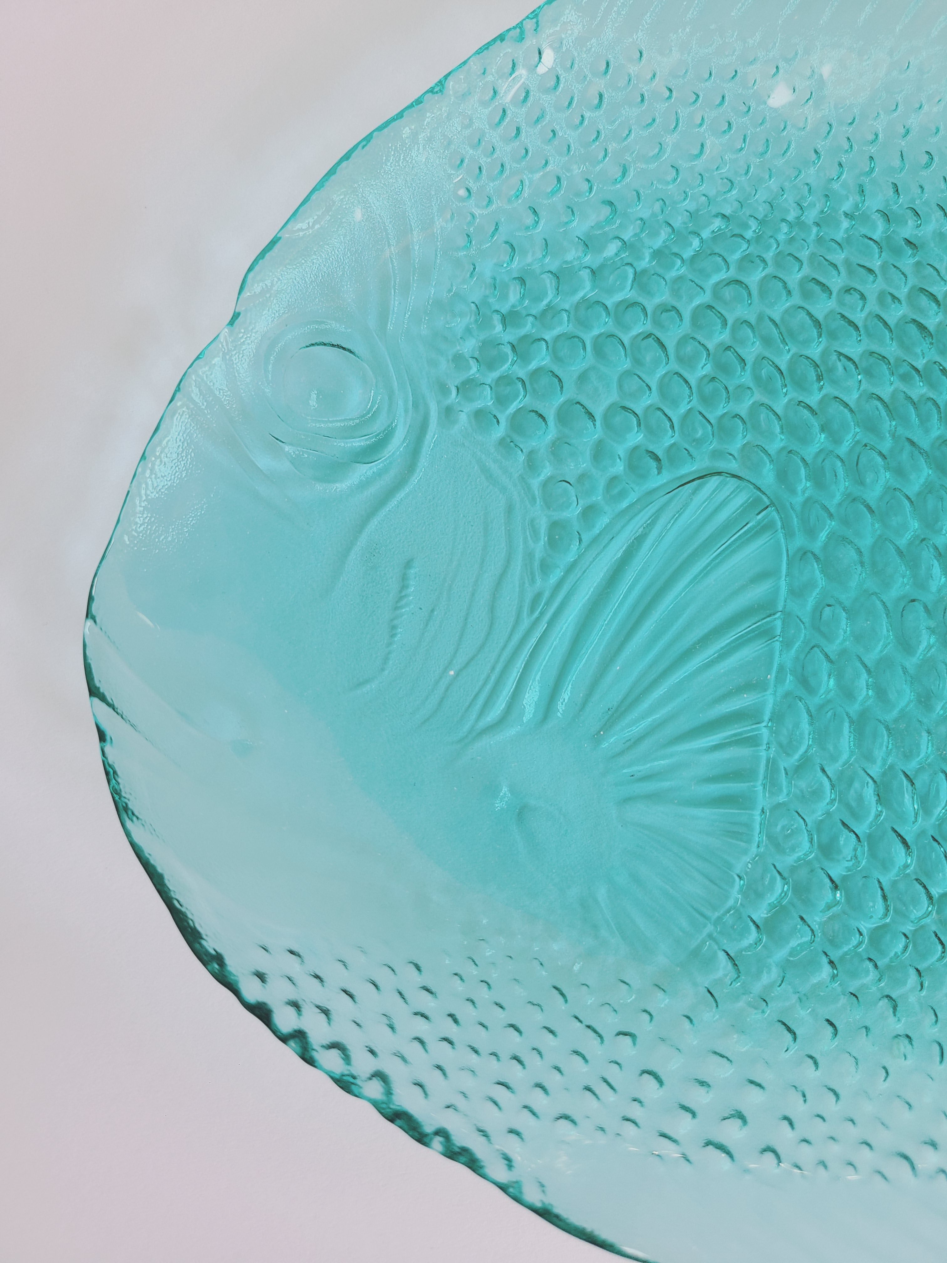 A close-up of vintage Arcoroc turquoise glass fish plate made in France. 
