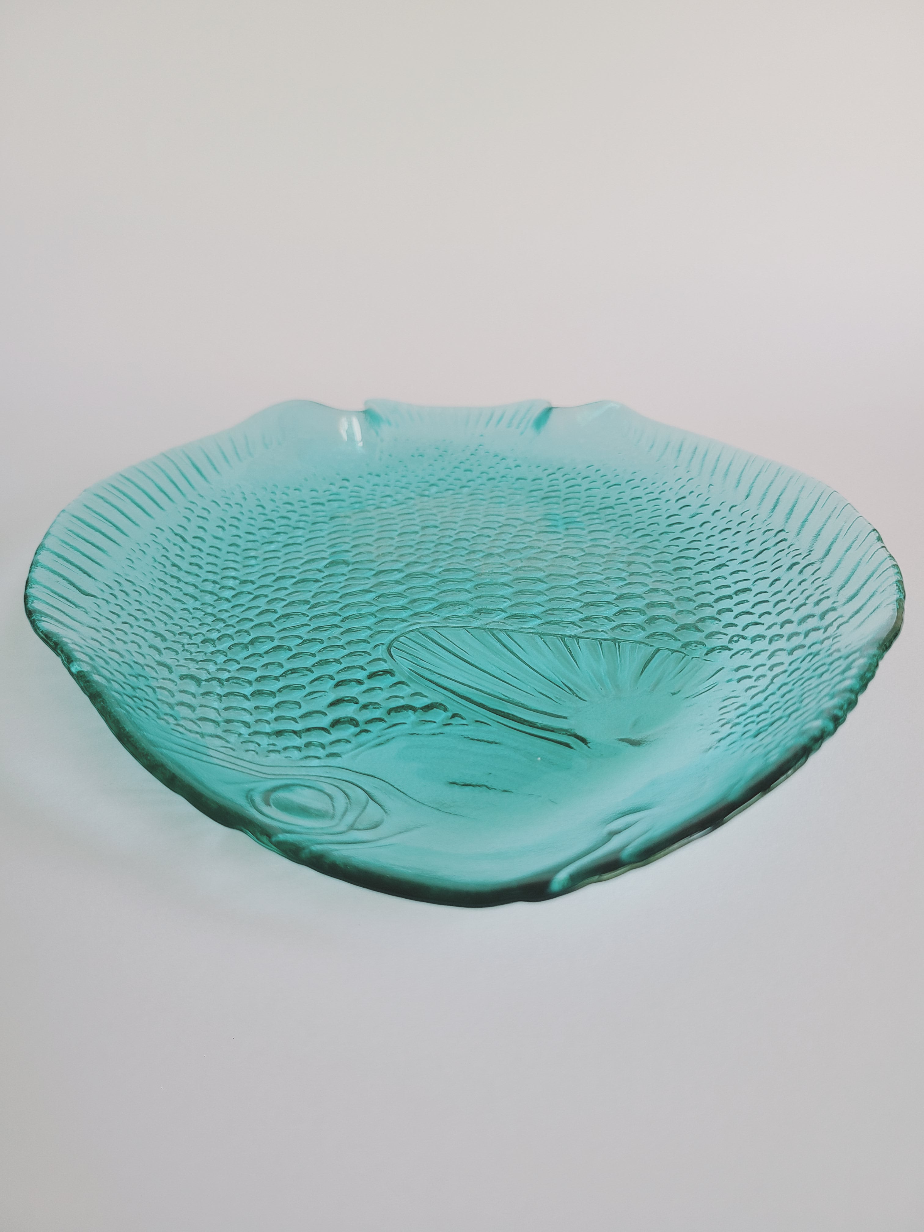 Close up of head of vintage Arcoroc turquoise glass fish plate made in France.
