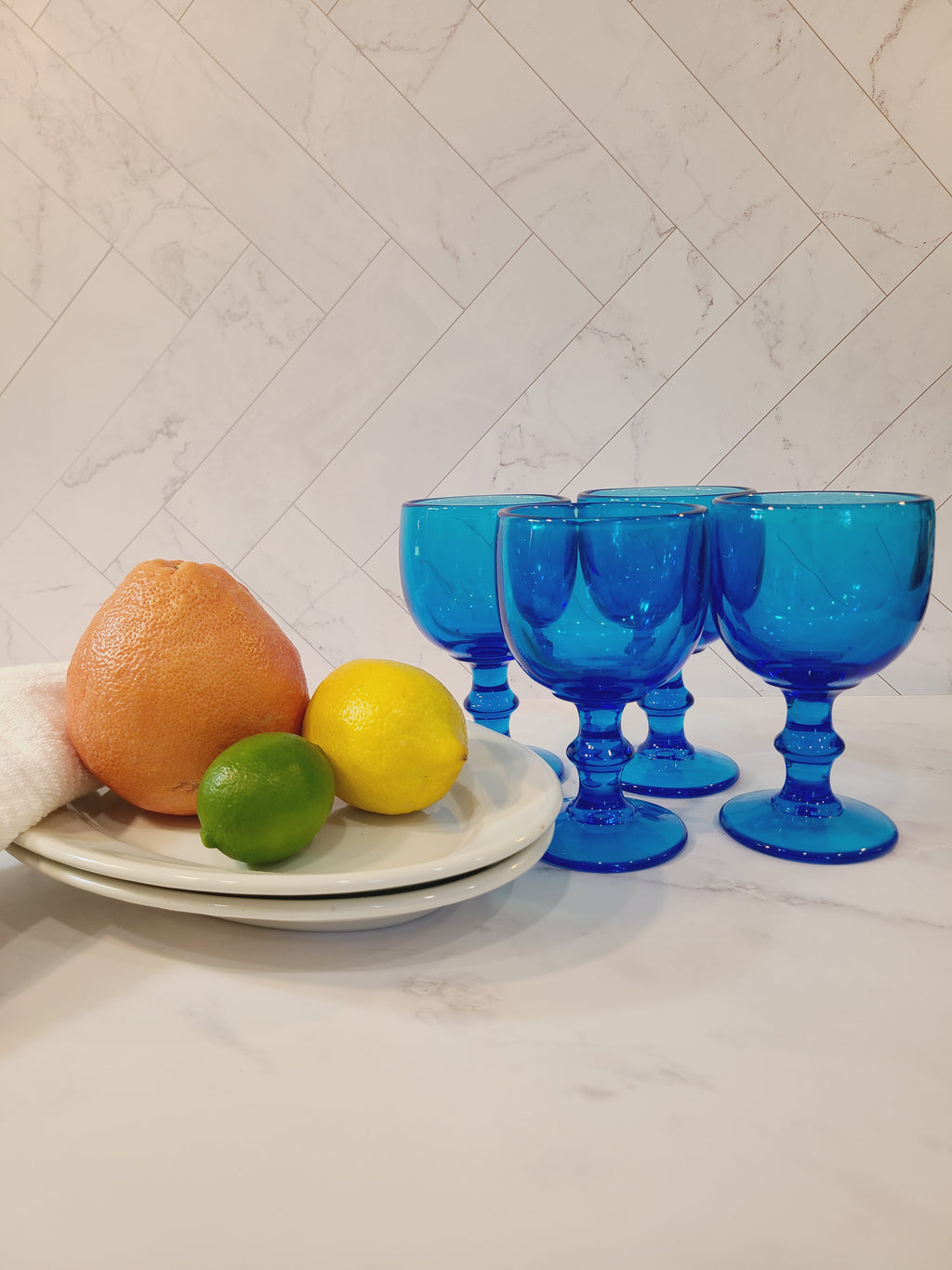 Vintage turquoise glass goblets by Imperial Glass Hoffman House displayed citrus fruit on a platter.