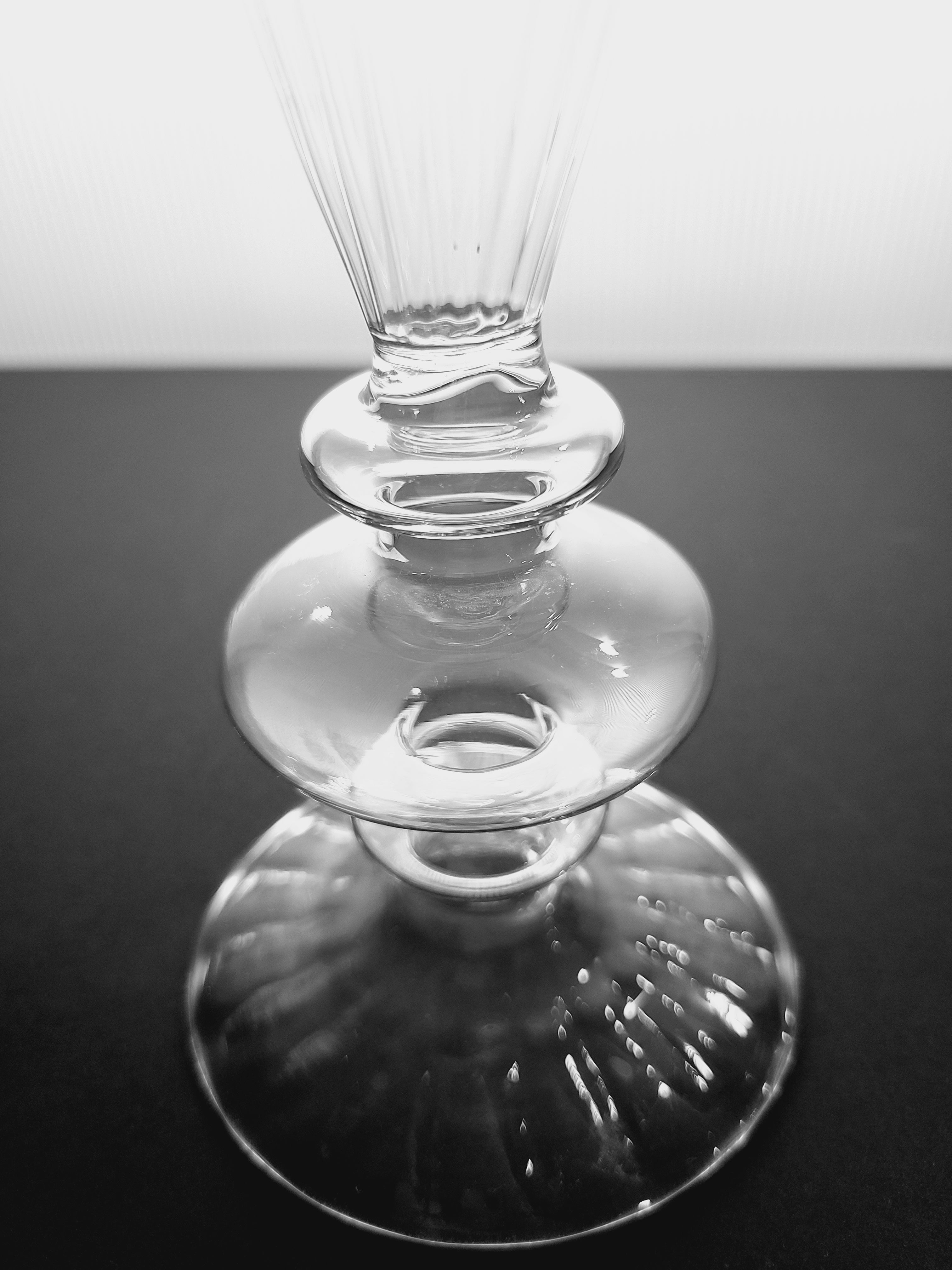 Close up of base of a clear glass vase on a dark background.