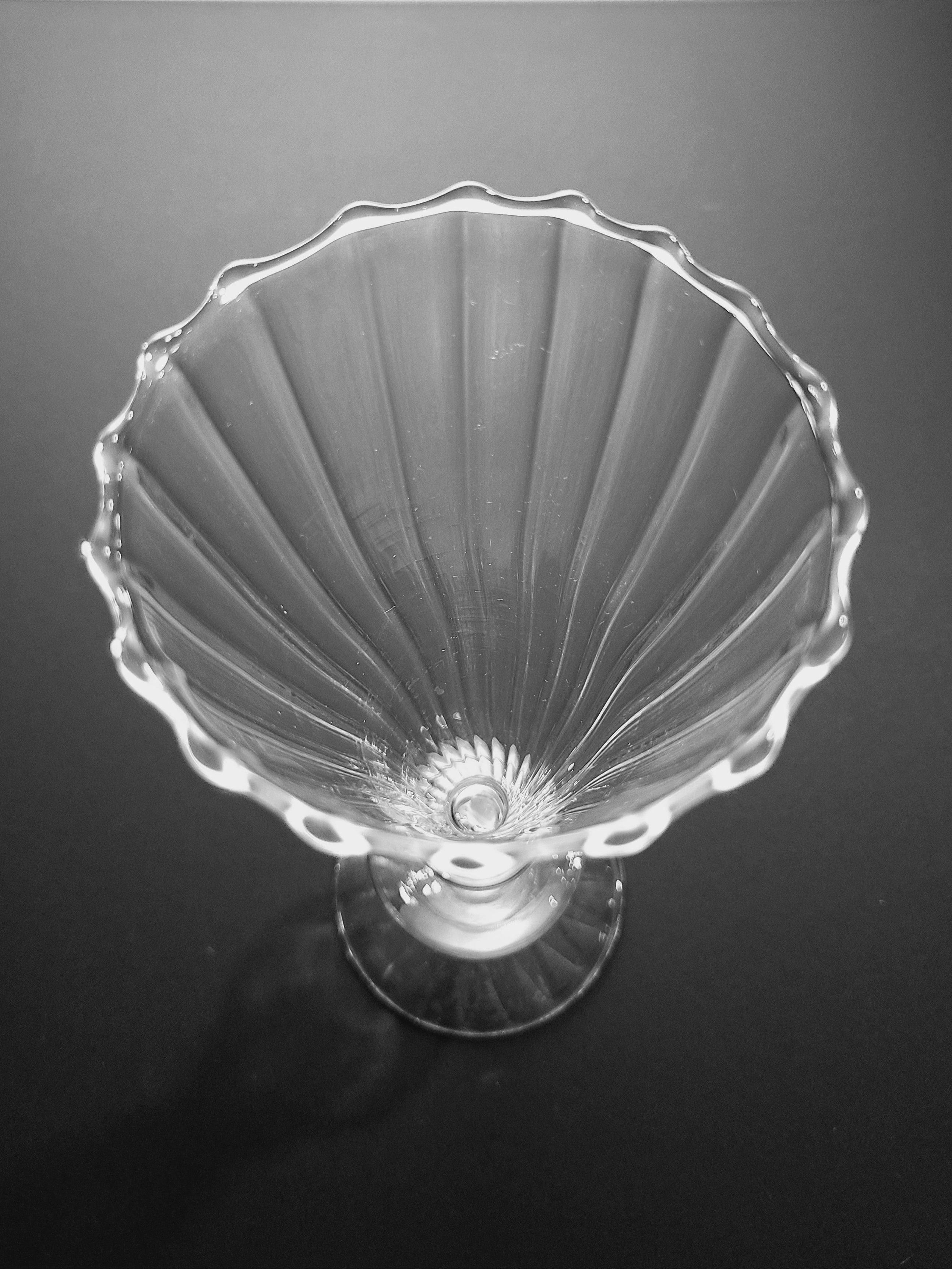 Close up of rim of clear glass vase against dark background.