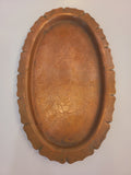 Vintage copper serving tray with a scalloped rim and etched floral patterns.