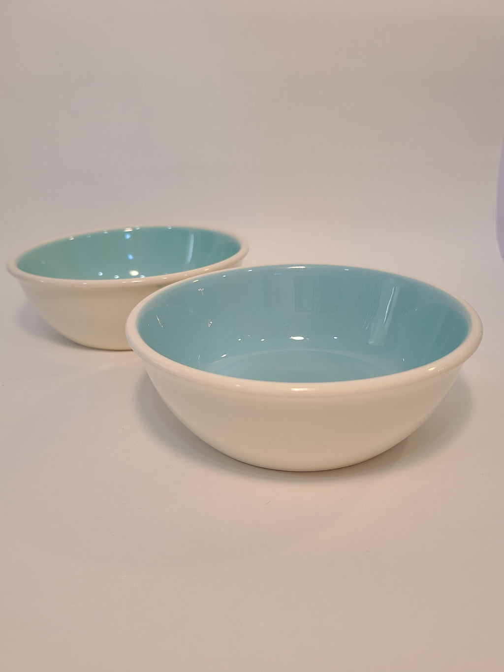 Side view of two vintage Chateau Buffet Stoneware Bowls with turquoise interior and white exterior.