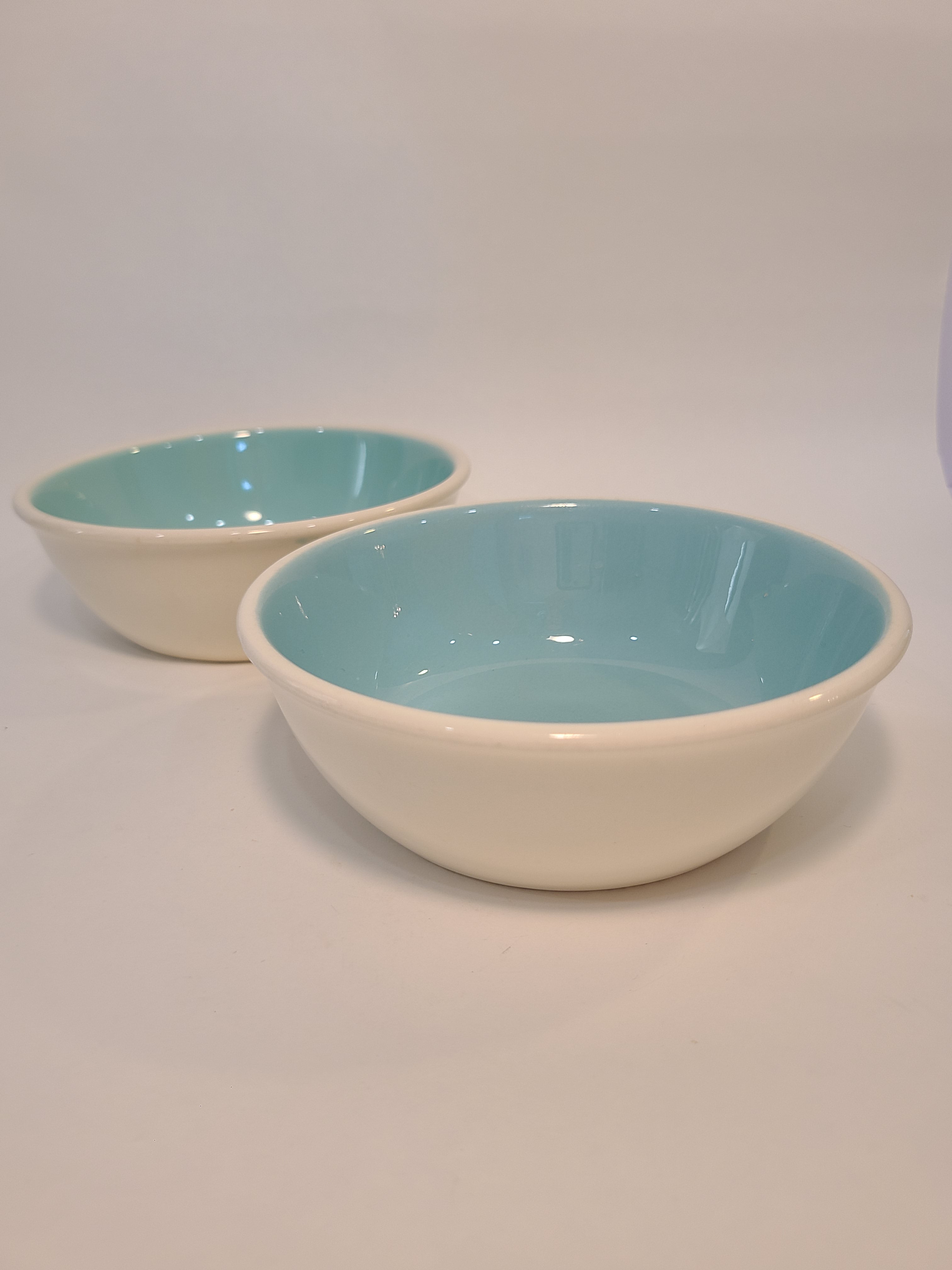 Side view of two vintage Chateau Buffet Stoneware Bowls with turquoise interior and white exterior.