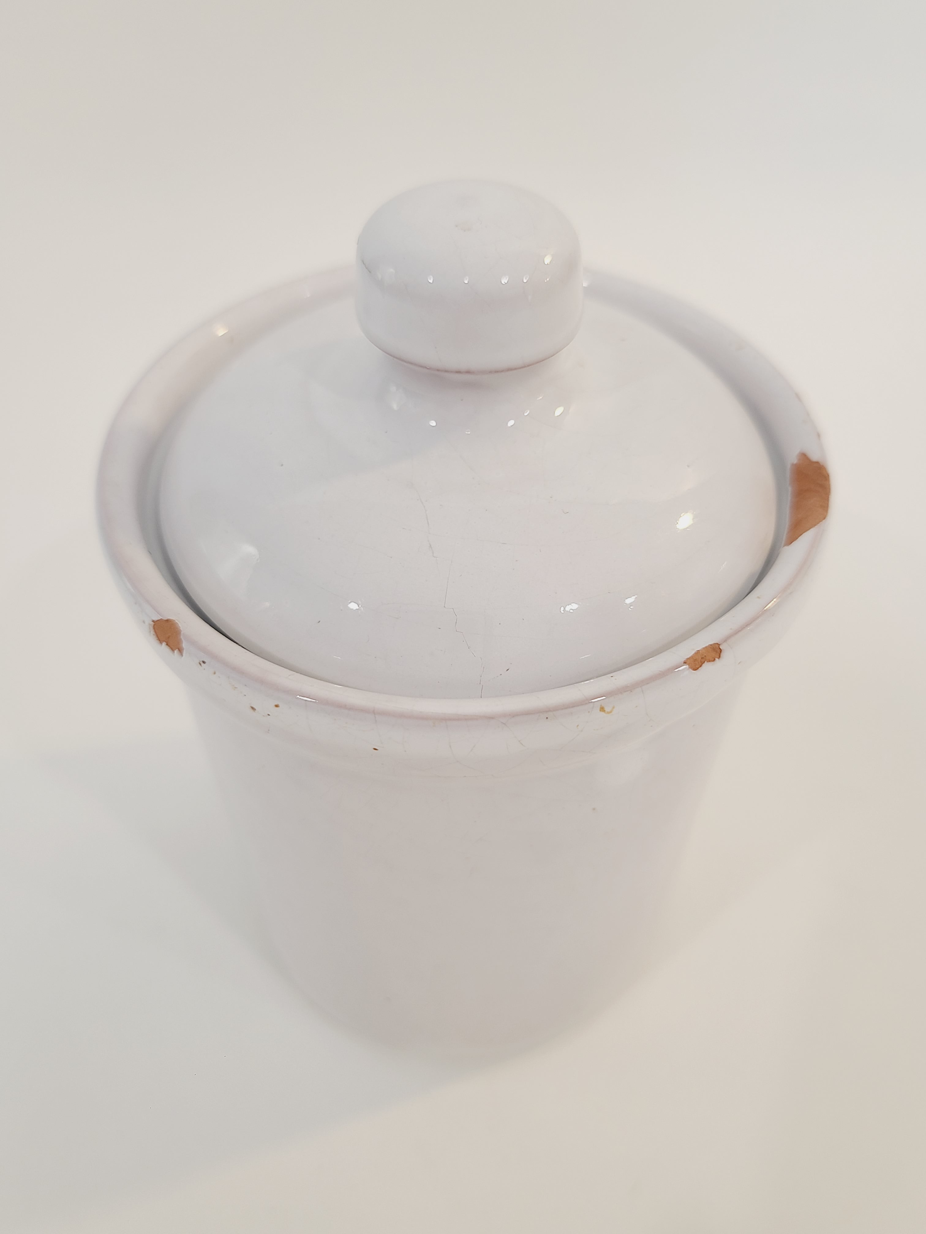 A white glazed ceramic lidded crock with a small knob on top, photographed on a plain white background.