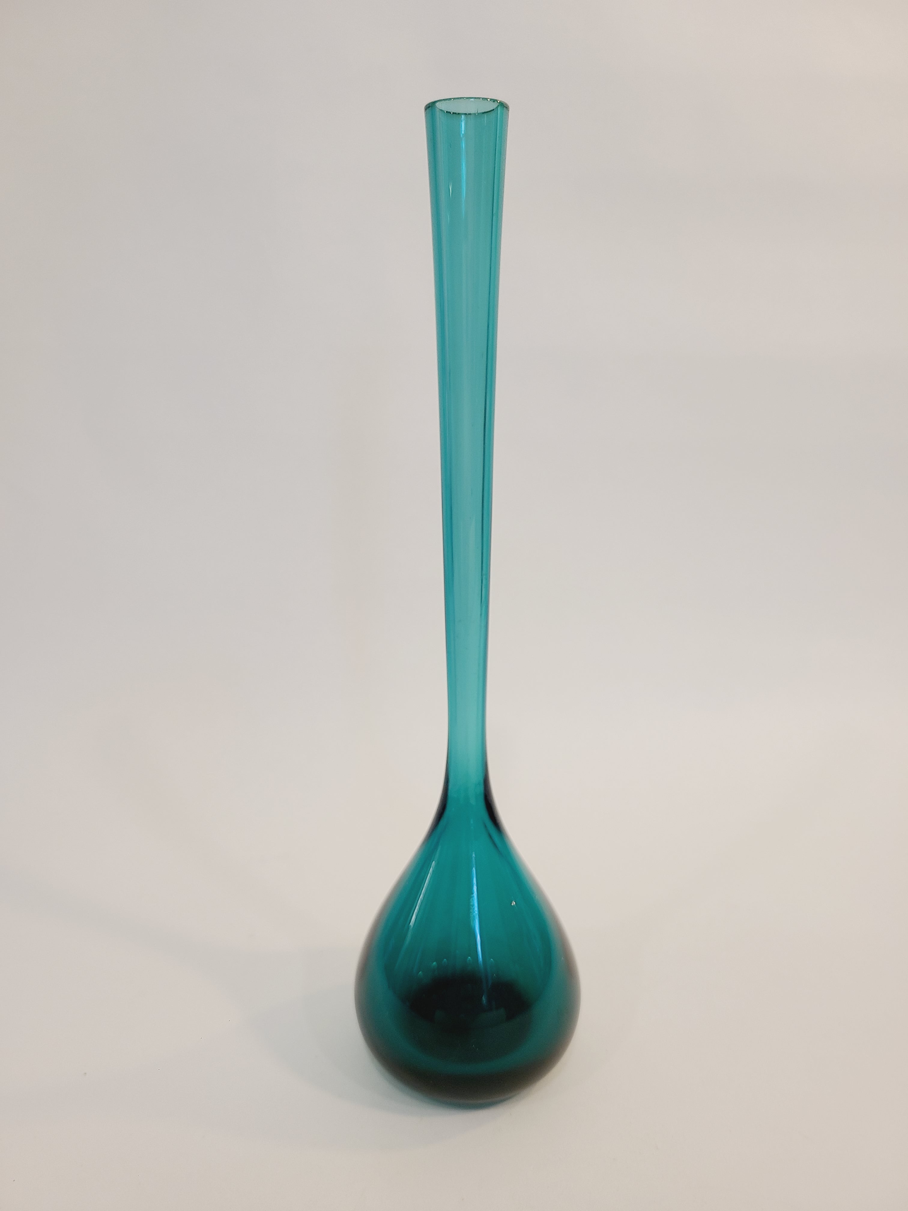 A translucent vintage teal glass vase with a long cylindrical neck and a bulbous rounded base made in Sweden, shown against a plain off-white background.