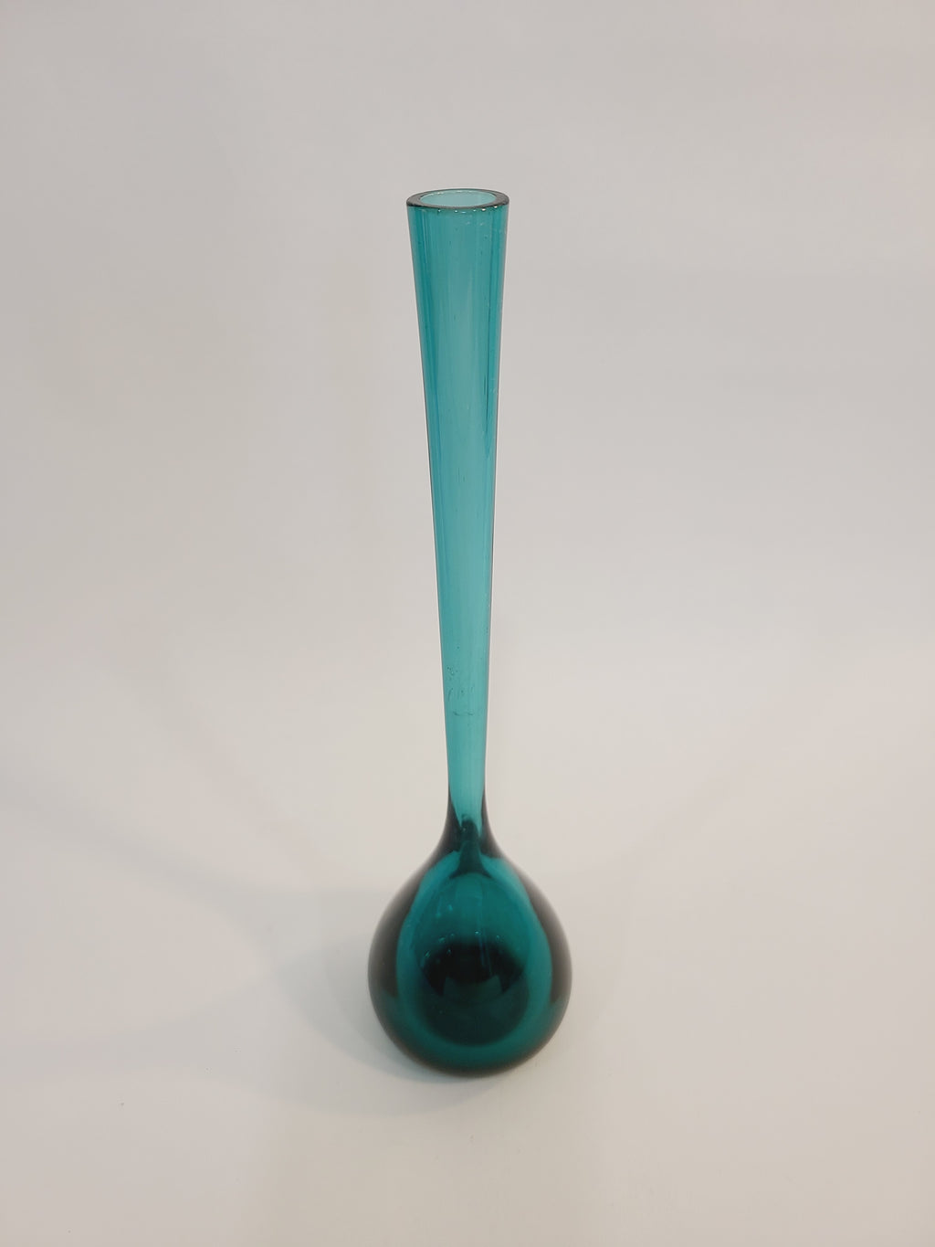 A translucent vintage teal glass vase with a long cylindrical neck and a bulbous rounded base made in Sweden.
