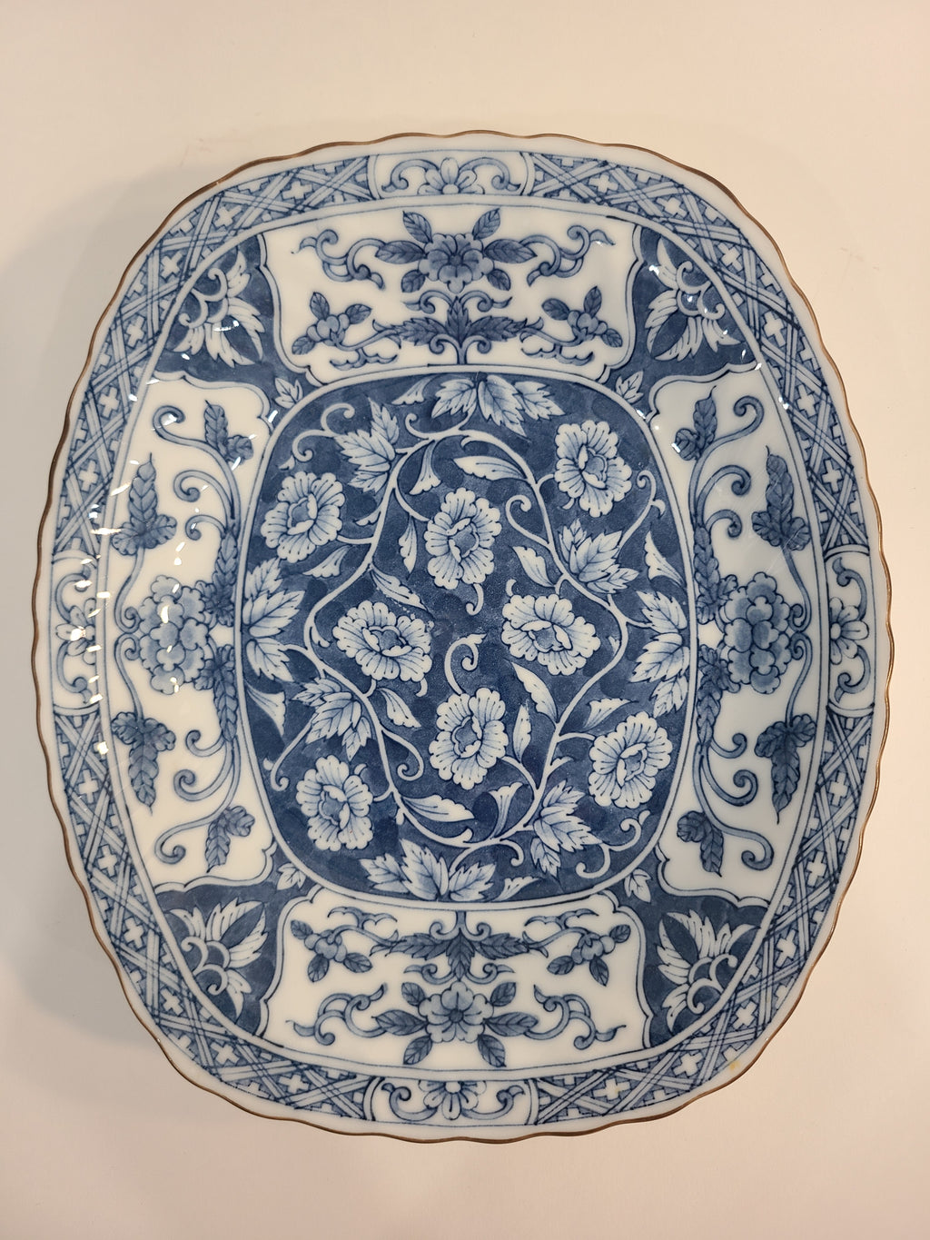 Overhead view of a vintage rectangular blue and white porcelain serving platter featuring an intricate floral and vine pattern made in Japan