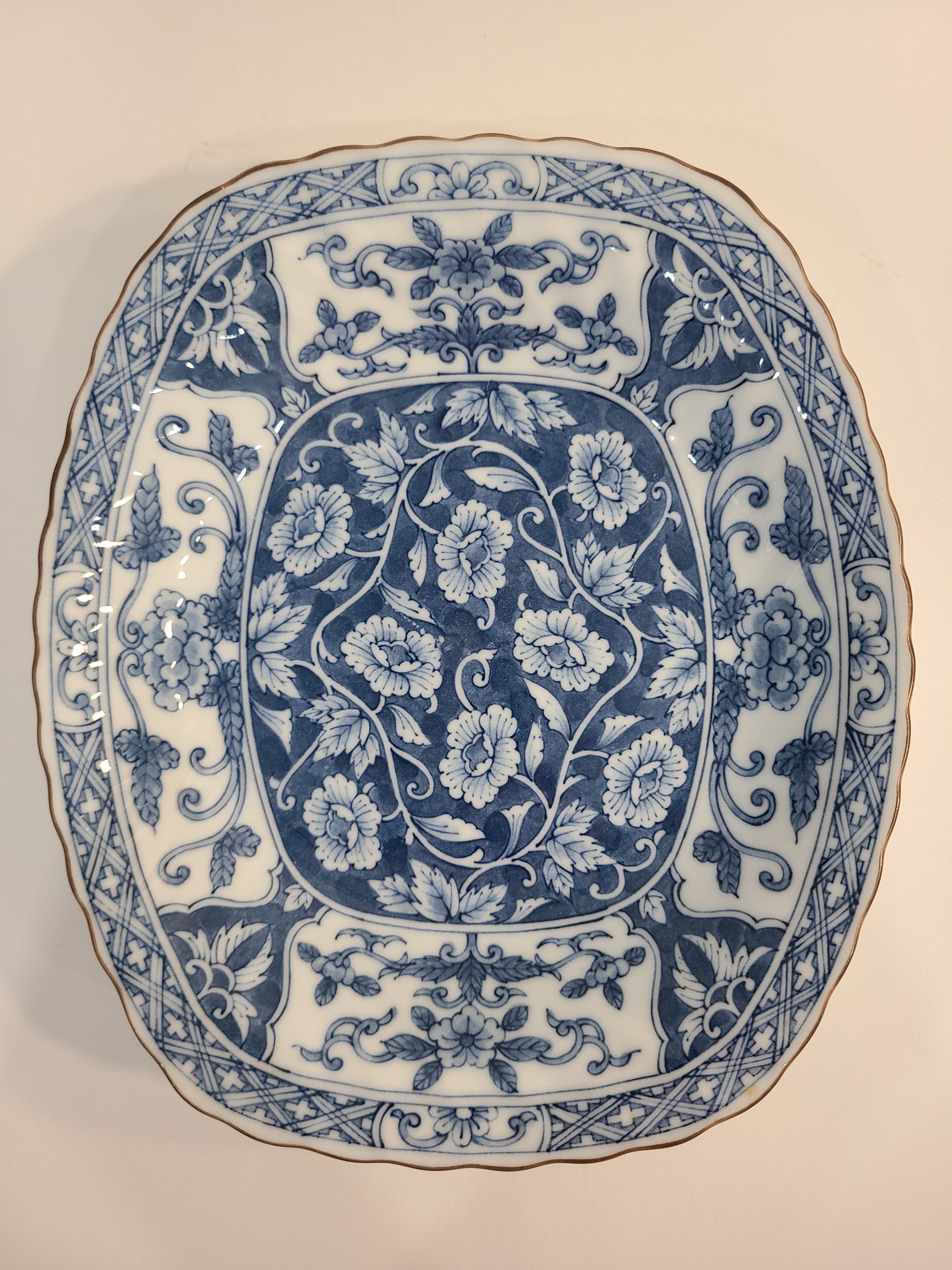 Overhead view of a vintage rectangular blue and white porcelain serving platter featuring an intricate floral and vine pattern made in Japan