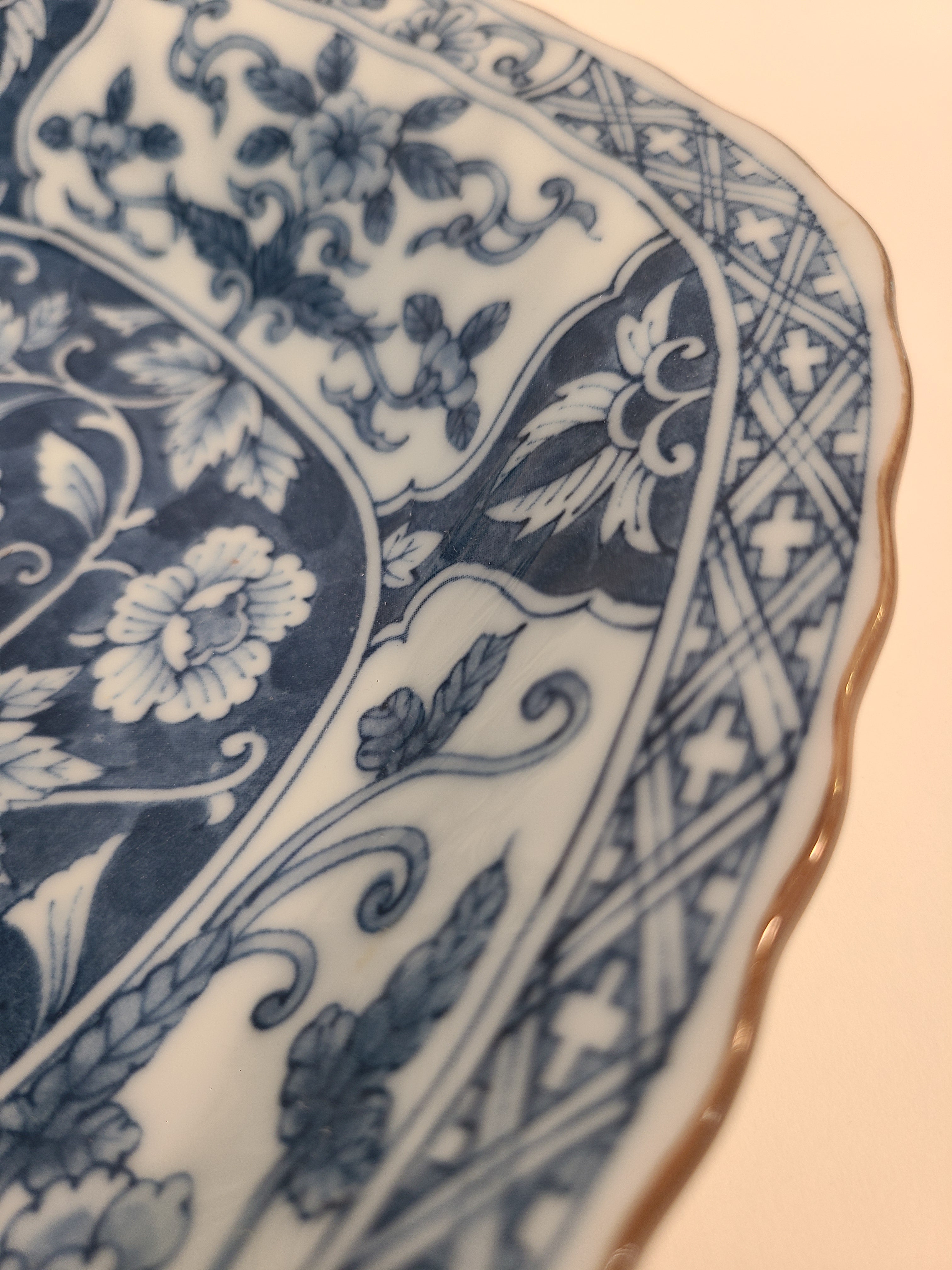 Close up of rim of A vintage rectangular blue and white porcelain serving platter featuring an intricate floral and vine pattern made in Japan.