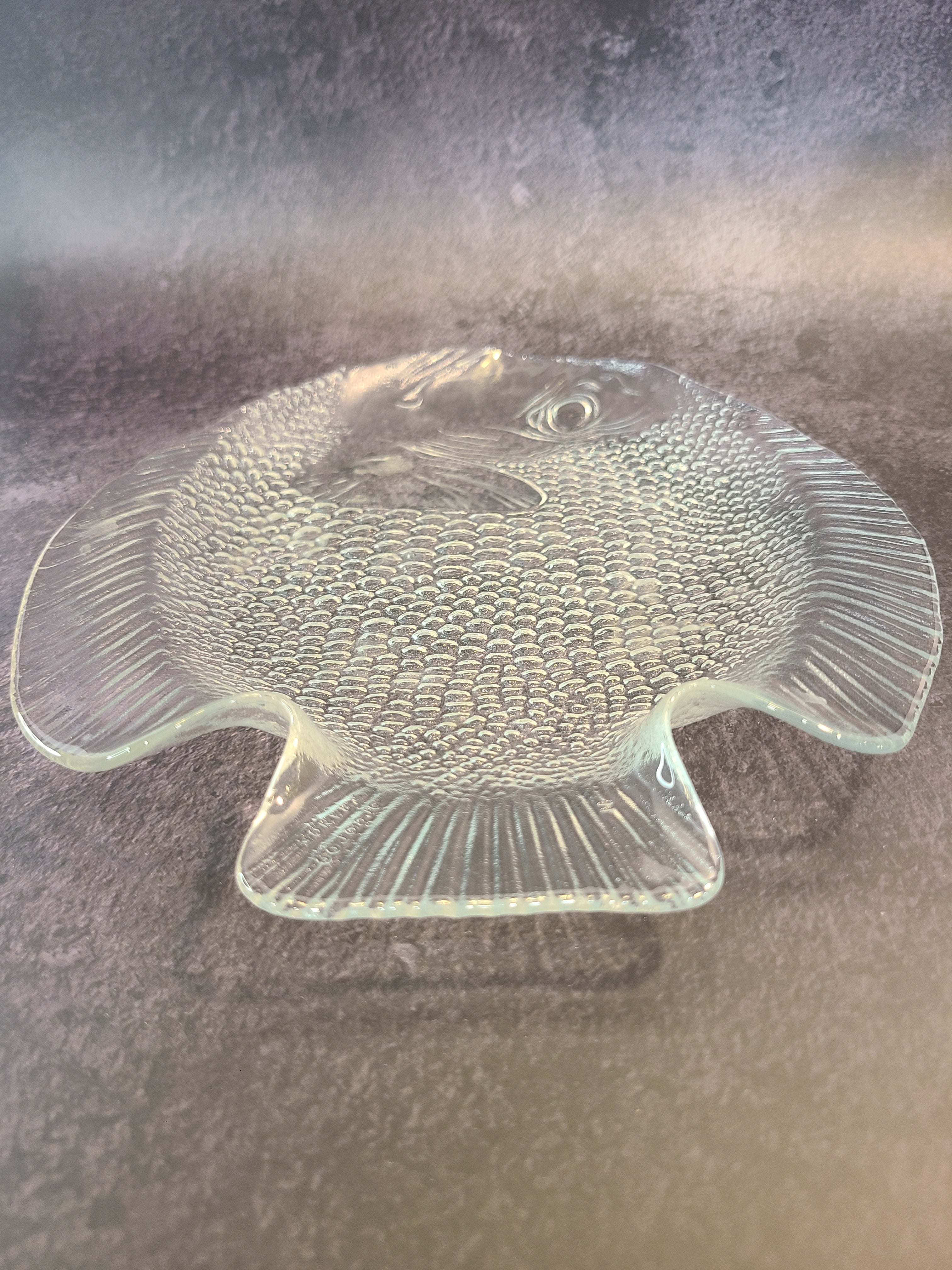 Close up of tail fin of vintage clear glass Arcoroc fish plate made in France.