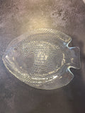 A vintage Arcoroc clear glass fish-shaped plate made in France with a textured, embossed pattern.