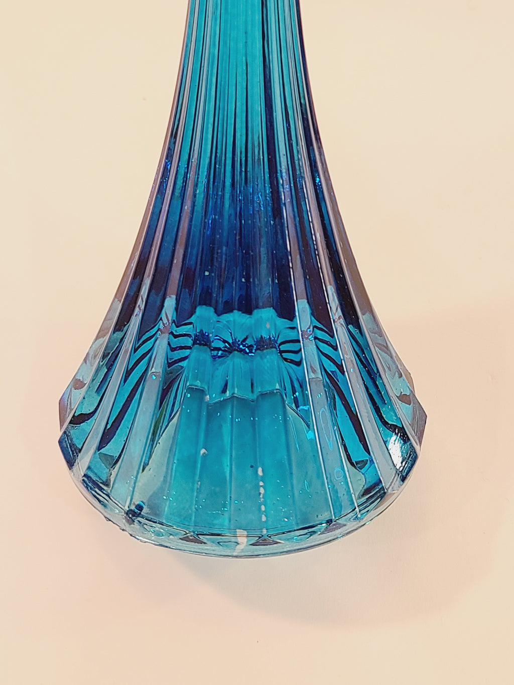 Close up of base of turquoise ridged glass candle holder, 1970s, 8 inches high, likely made in USA.