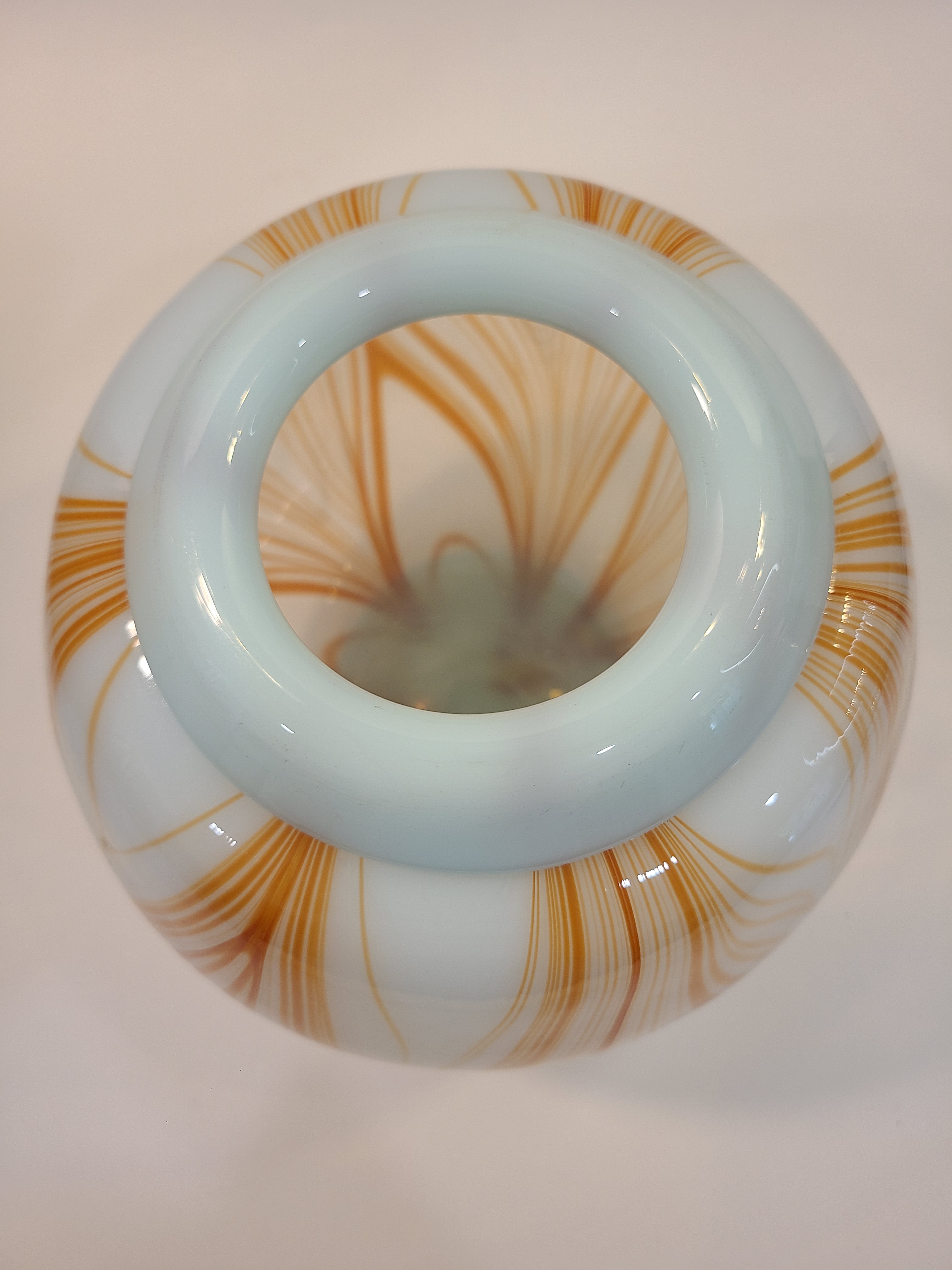 Top view of Handblown artisan glass vase in shape of a sphere, very pale aqua with orange feather-raked accents, 7 inches diameter.