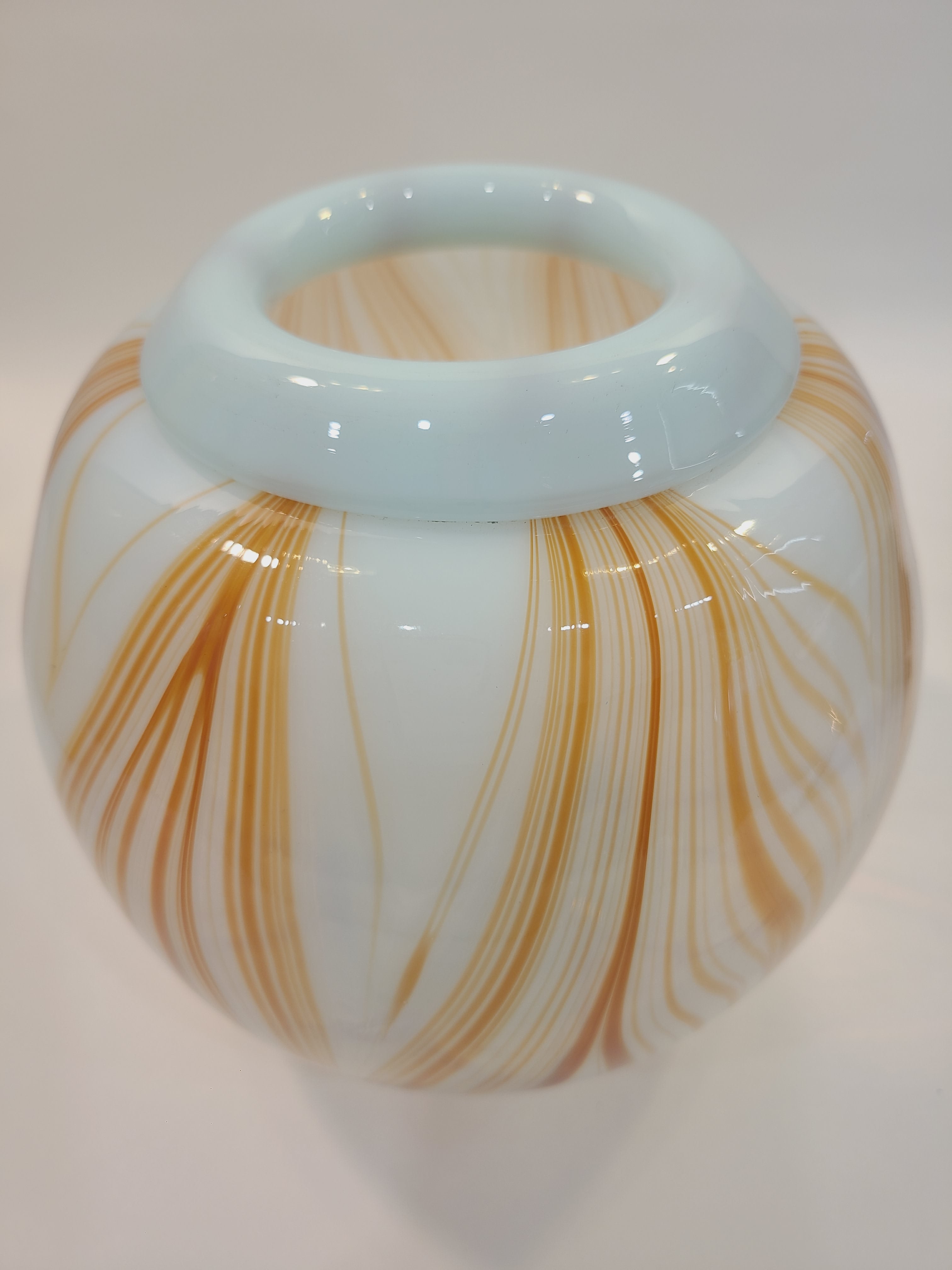 Handblown artisan glass vase in shape of a sphere, very pale aqua with orange feather-raked accents, 7 inches diameter on light background.