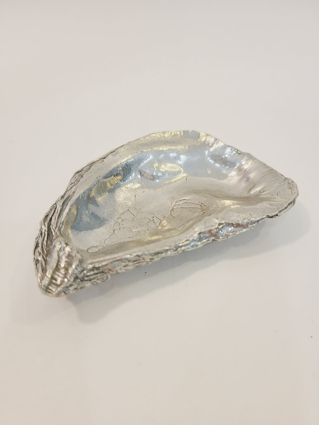 Pewter oyster shell dish, 3.75 inches by 2.25 inches on light background.