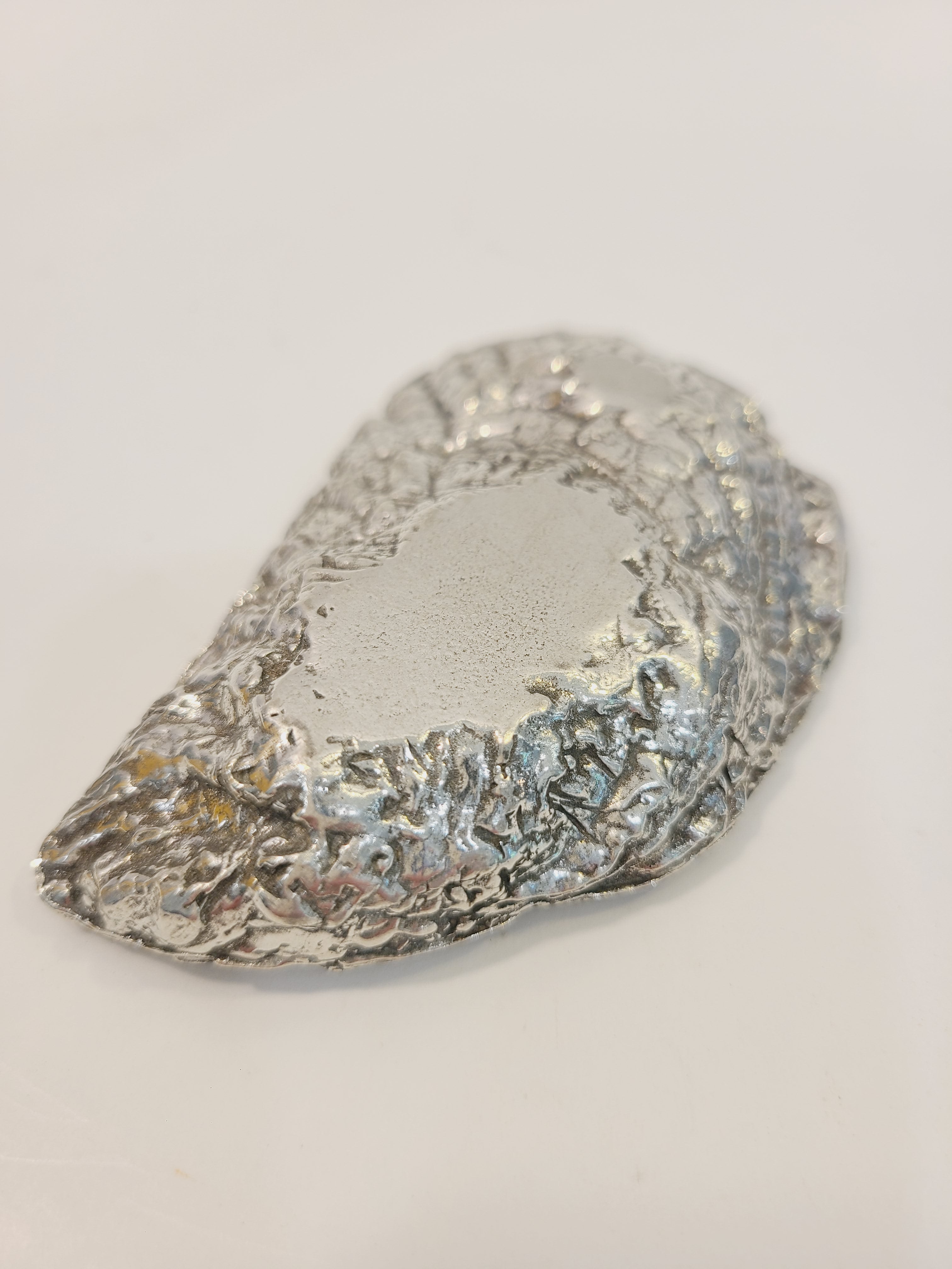 Bottom of Pewter oyster shell dish, 3.75 inches by 2.25 inches.