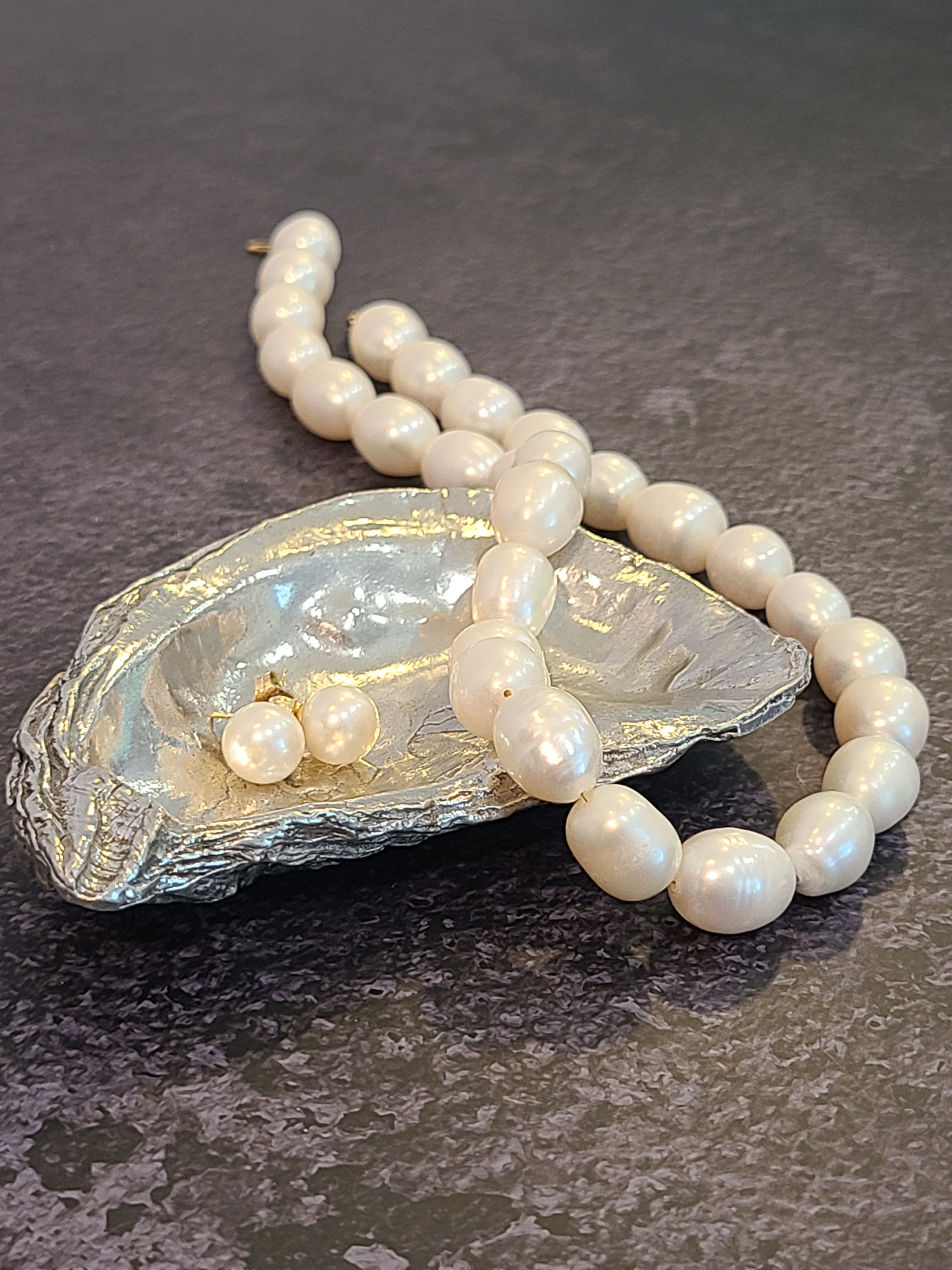 Pewter oyster shell dish, 3.75 inches by 2.25 inches displayed holding pearl earrings and necklace.