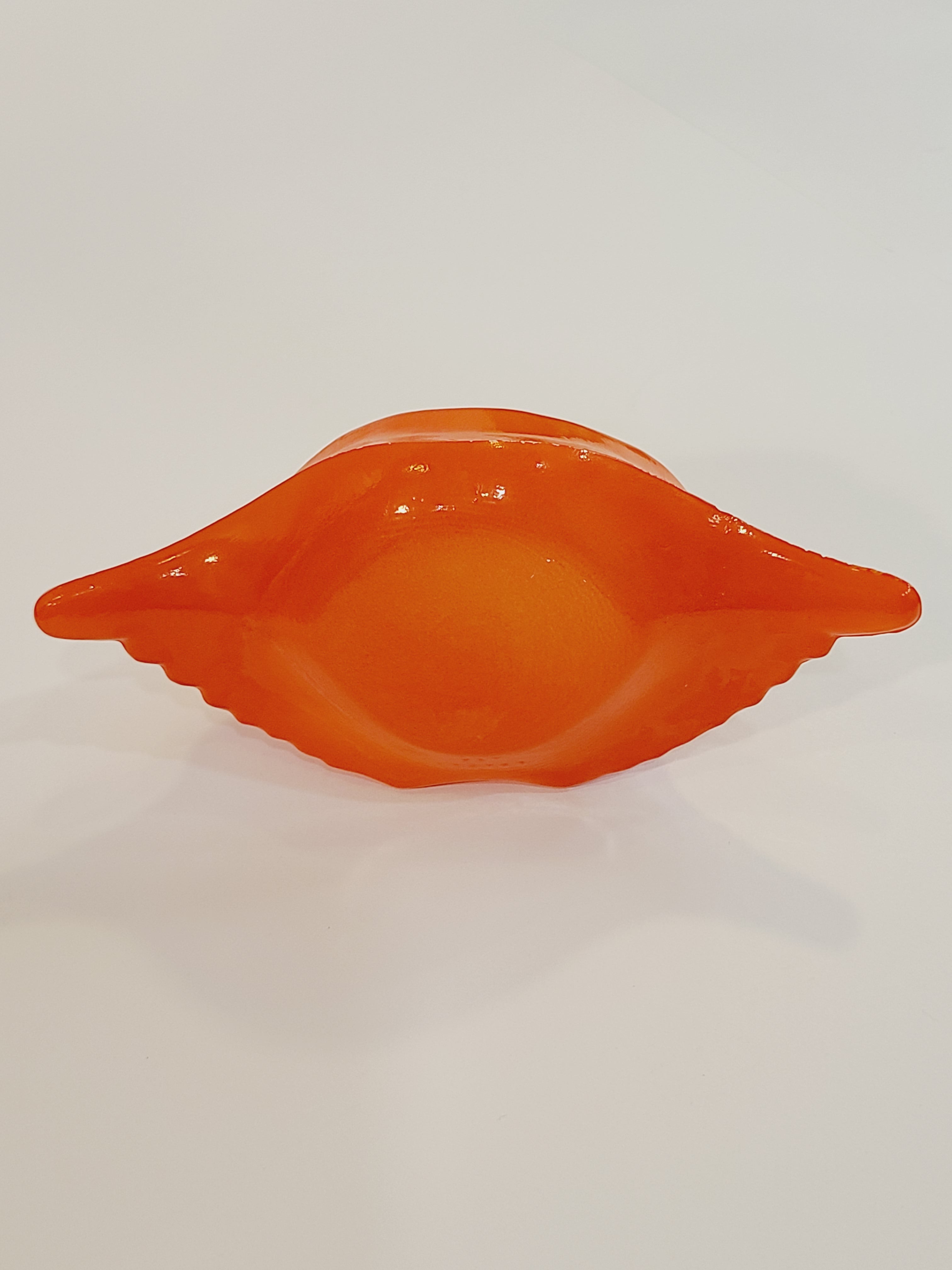 Bottom of Red-orange Glasbake glass dish shaped like a crab shell, 5.75 inches by 2.75 inches.