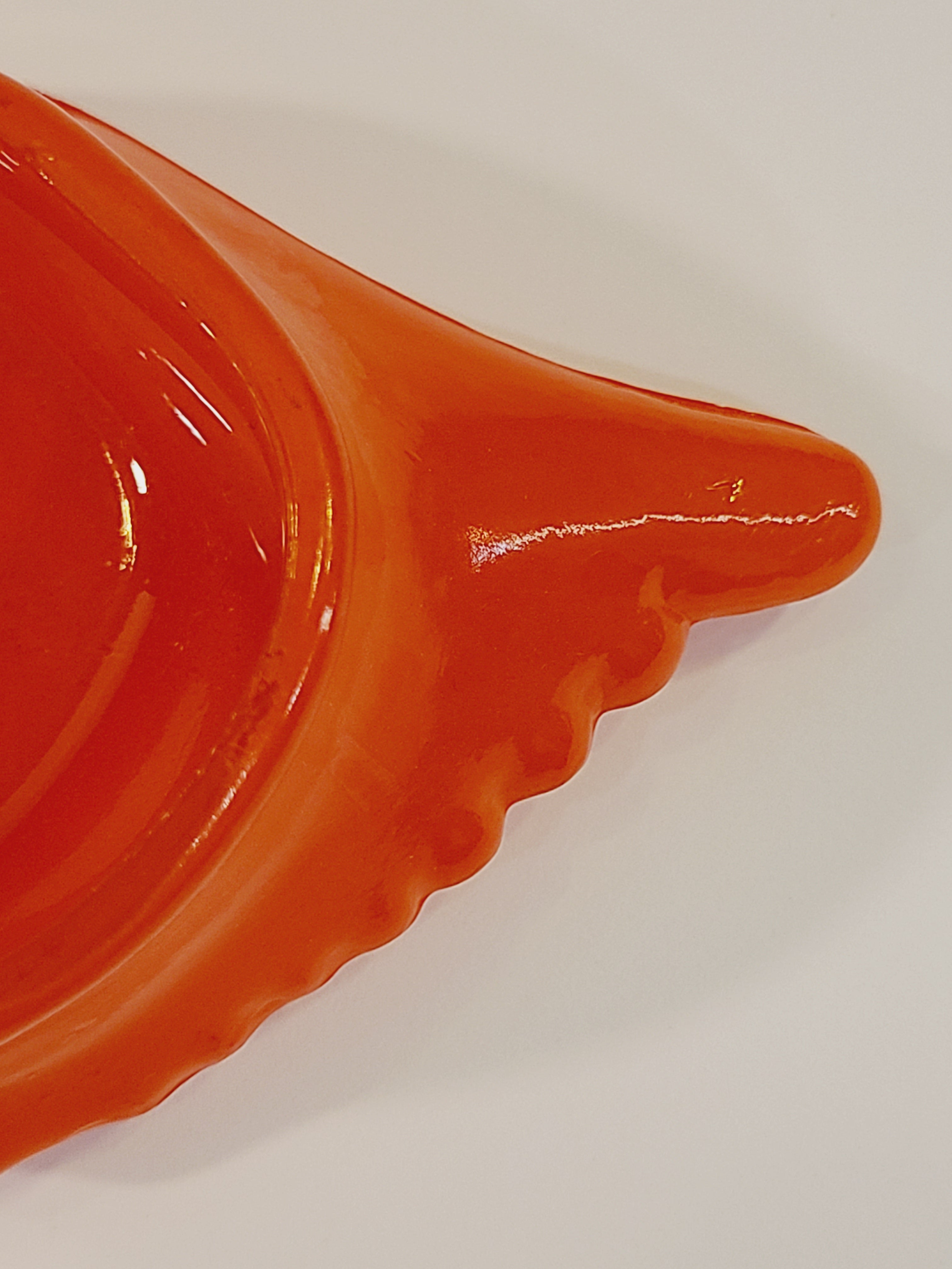Close up of Red-orange Glasbake glass dish shaped like a crab shell, 5.75 inches by 2.75 inches.