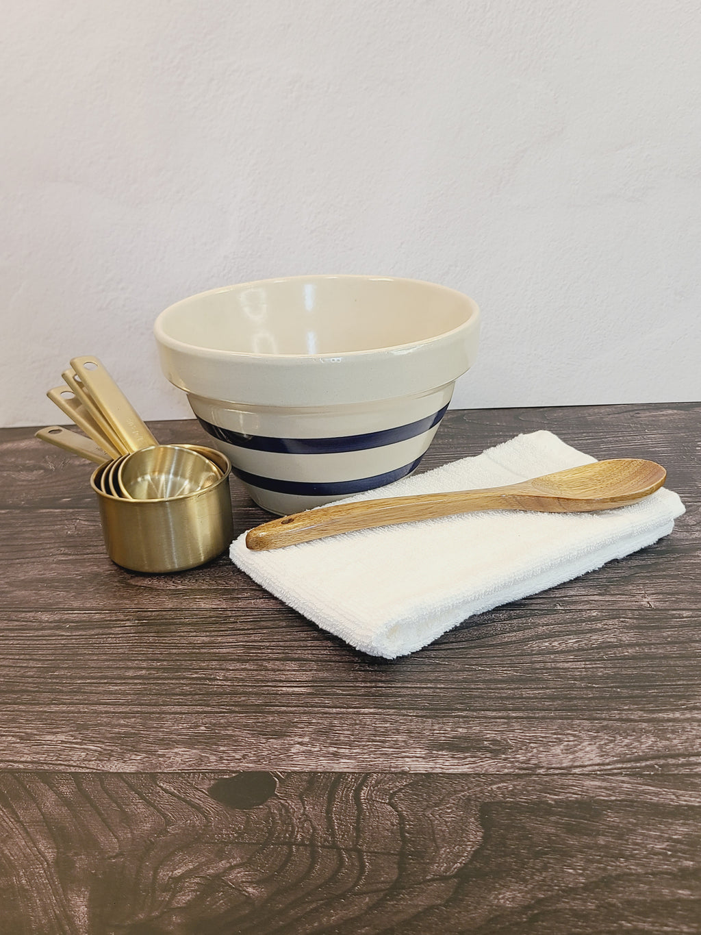 Vintage RRP Co. stoneware mixing bowl styled with brass measuring cups and wooden spoon on rustic wood surface, blue stripe pottery