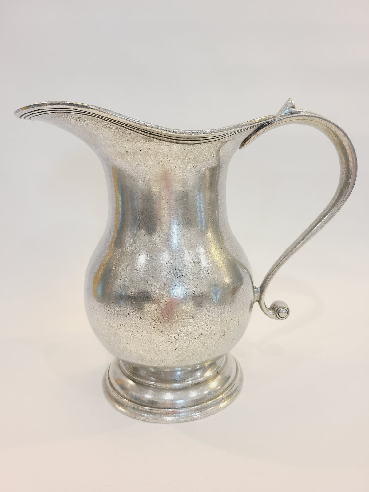 Vintage pewter water pitcher with S-scroll handle and stepped tiered foot, European artisan design circa late 1970s–1980s, 8.25 inches tall