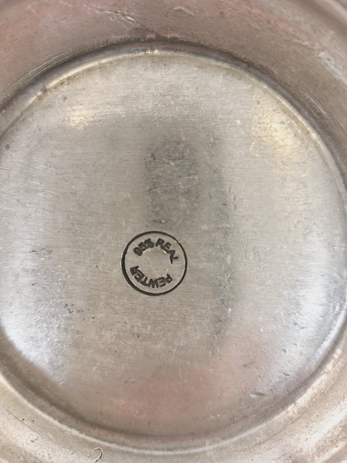Close-up of 95% Real Pewter circular hallmark stamp on base of vintage European pewter pitcher, certifying lead-free food-safe composition