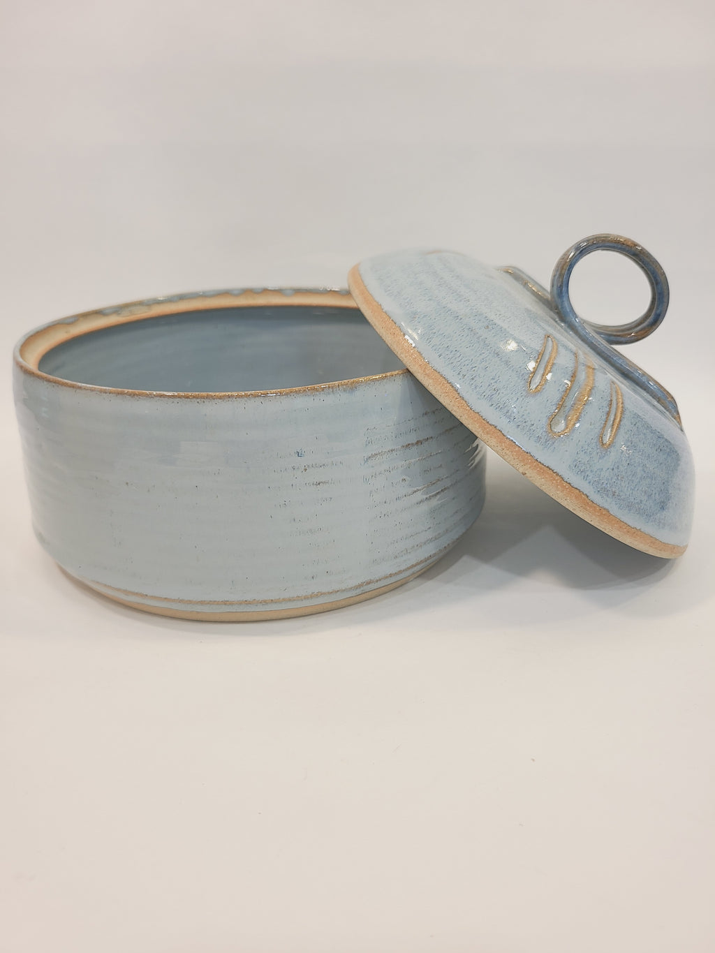 Pat Look studio pottery covered bowl with lid removed showing pale blue glazed interior and unglazed natural clay rim, hand-thrown stoneware coastal decor