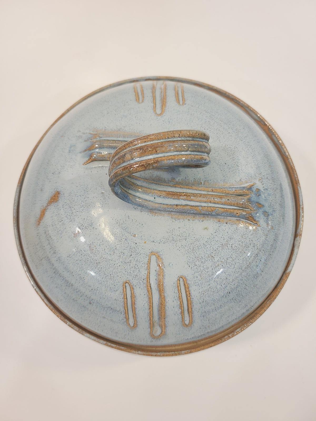 Overhead view of Pat Look studio pottery lid showing loop handle and incised decorative marks on pale blue speckled glaze, signed American studio craft