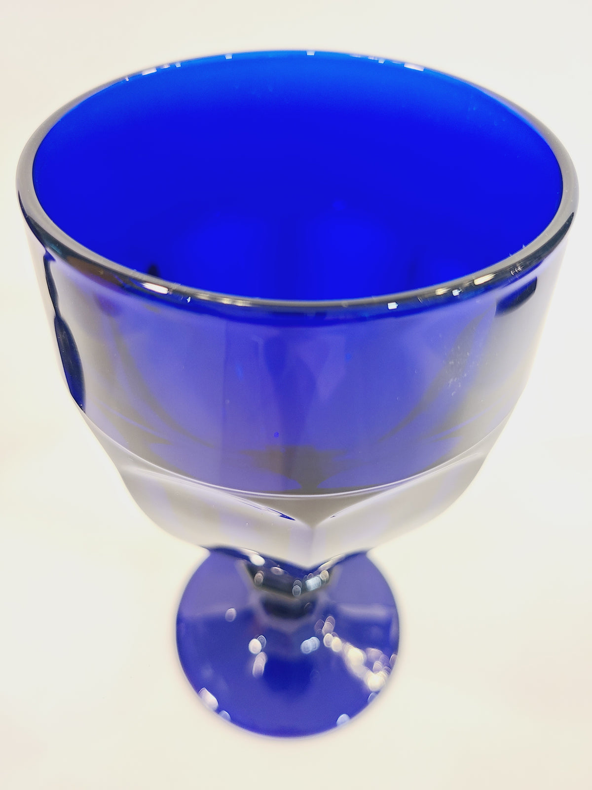Overhead view into Libbey Gibraltar cobalt blue goblet showing deep saturated blue interior and angular faceted rim, vintage collectible barware