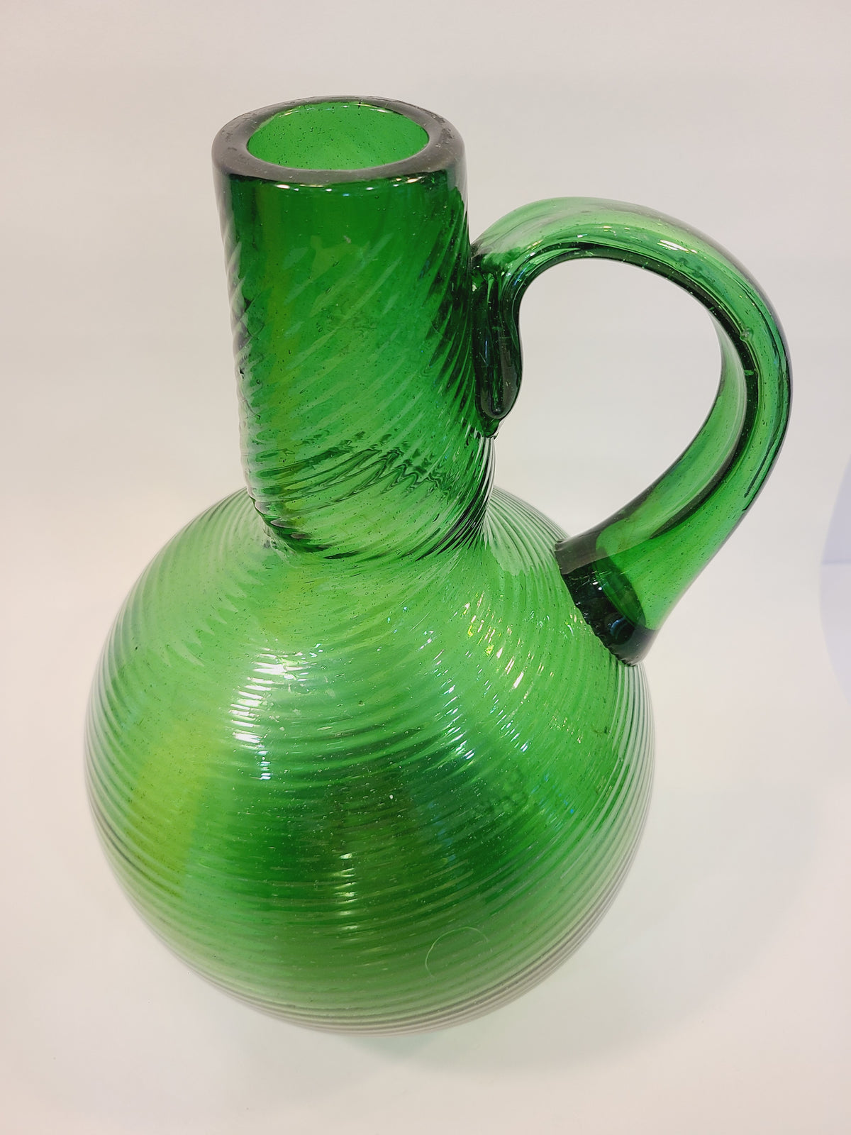Top-angle view of mid-century emerald green spiral glass jug vase showing open neck and applied handle detail
