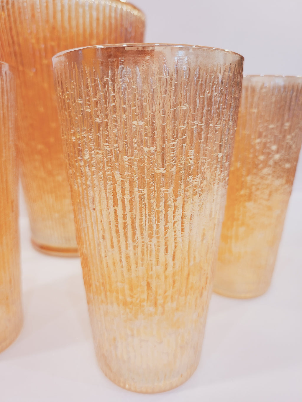 Close-up of Jeannette Glass Marigold carnival glass tumblers showing deeply molded Tree Bark texture and iridescent metallic luster, Depression-era collectible glassware