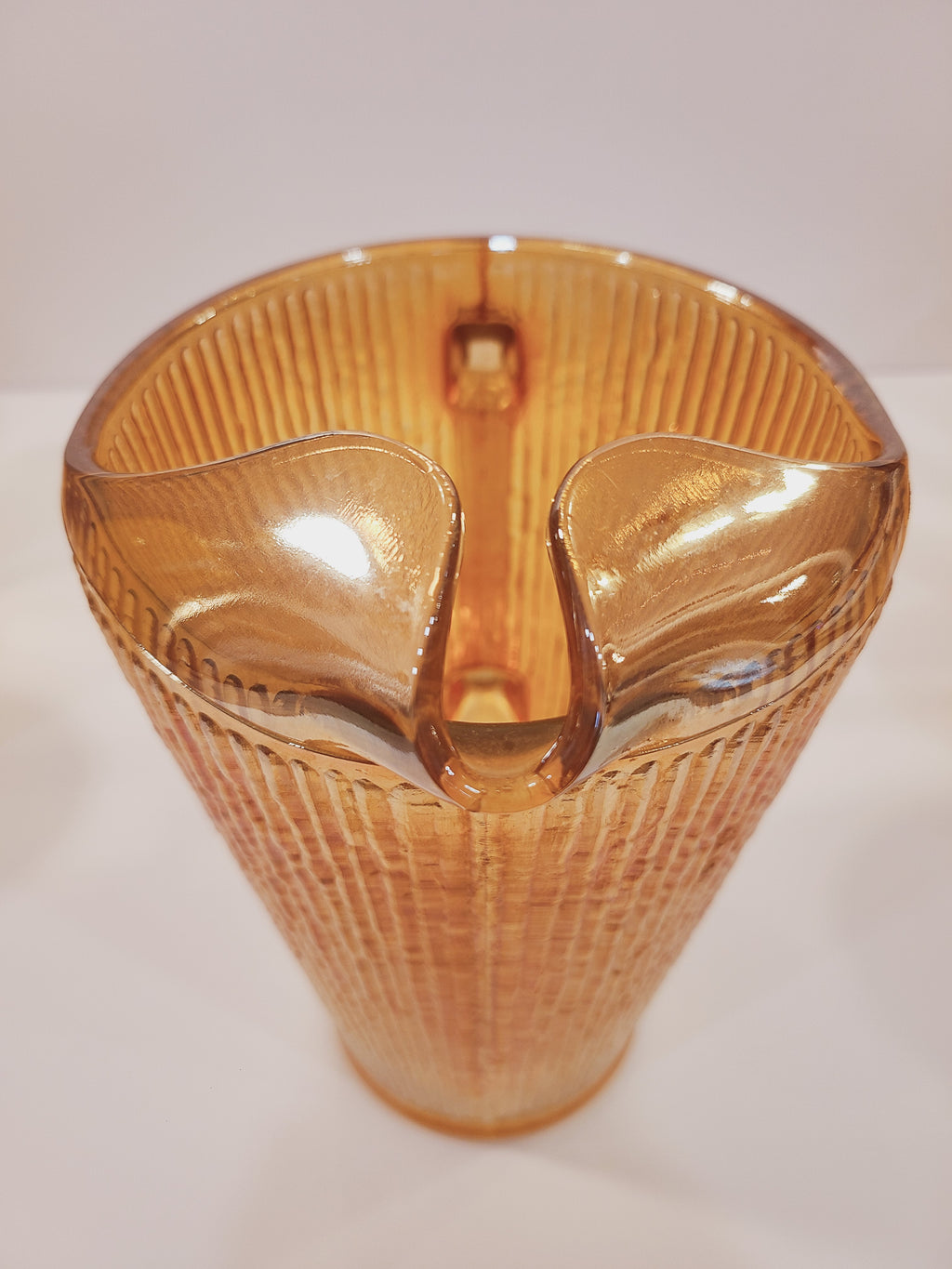 Close-up of molded ice lip spout on Depression-era Jeannette Glass Marigold carnival glass pitcher, Tree Bark pattern detail