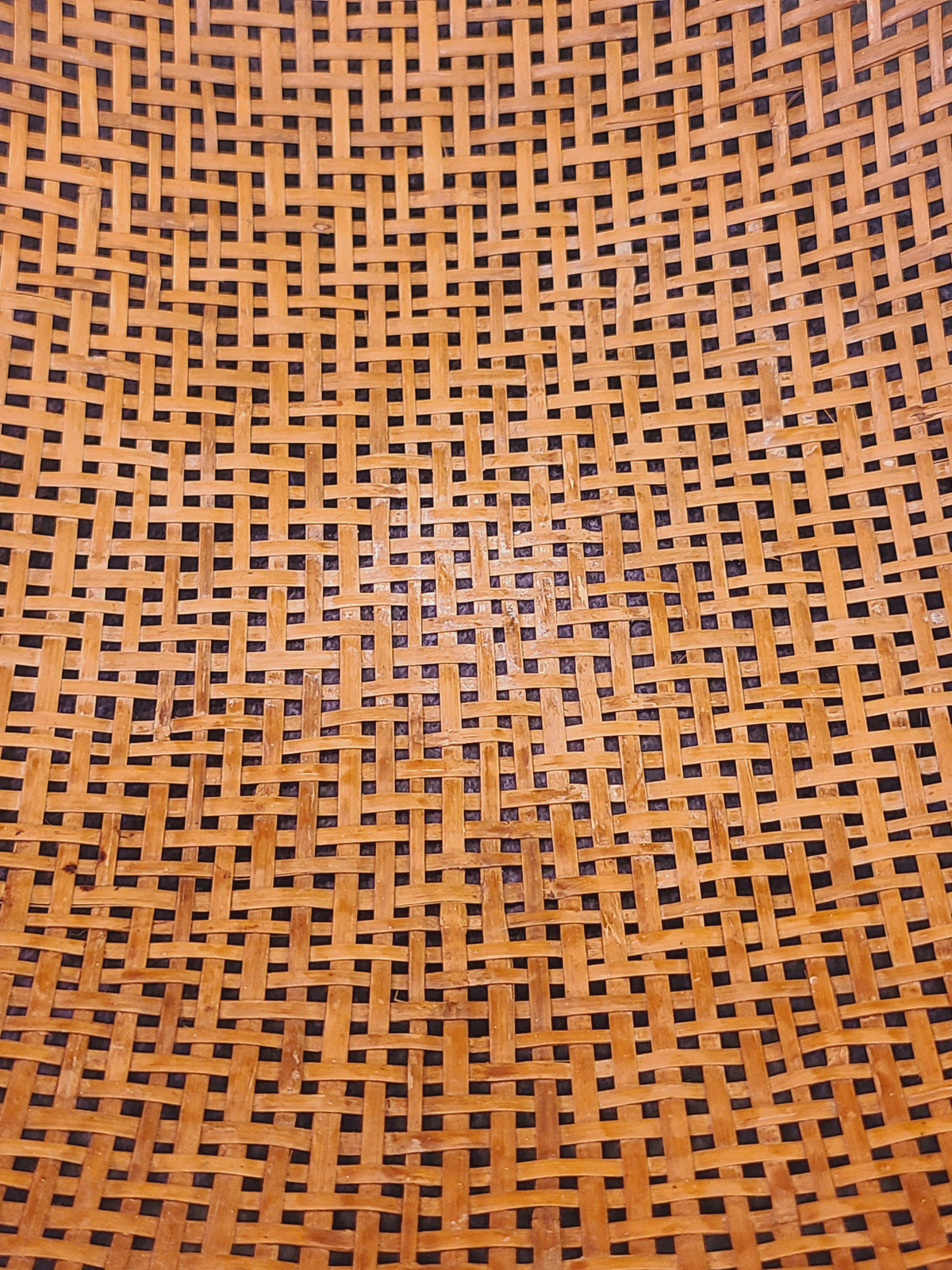Interior extra close-up of hand-woven split bamboo basket showing aged amber patina and open lattice weave, mid-century East Asian folk craft
