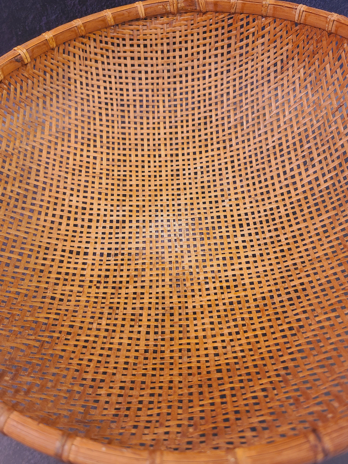 Interior close-up of hand-woven split bamboo basket showing aged amber patina and open lattice weave, mid-century East Asian folk craft