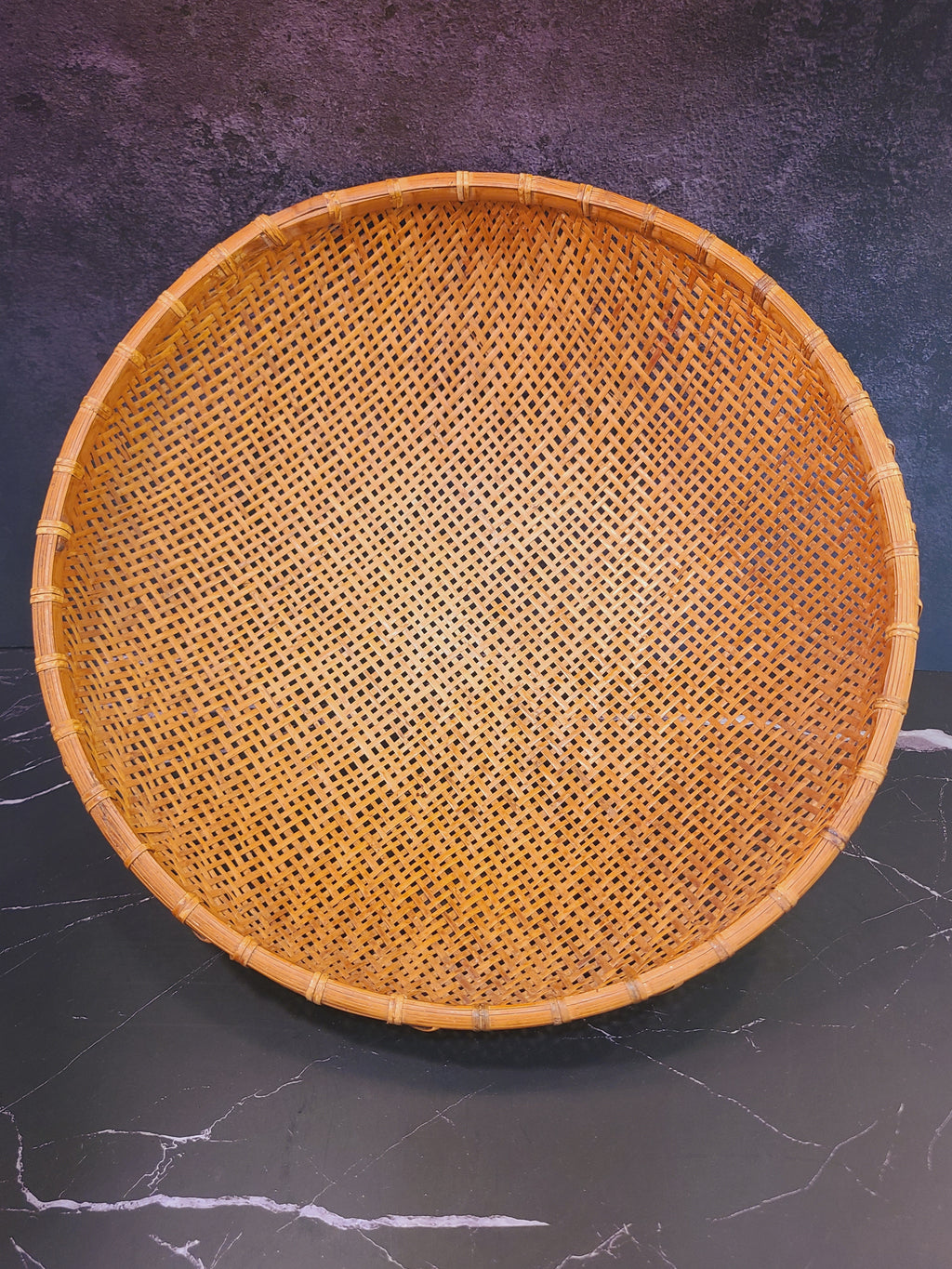 Overhead view of large round hand-woven bamboo winnowing basket on dark surface, 16.5 inch diameter, East Asian vintage folk art