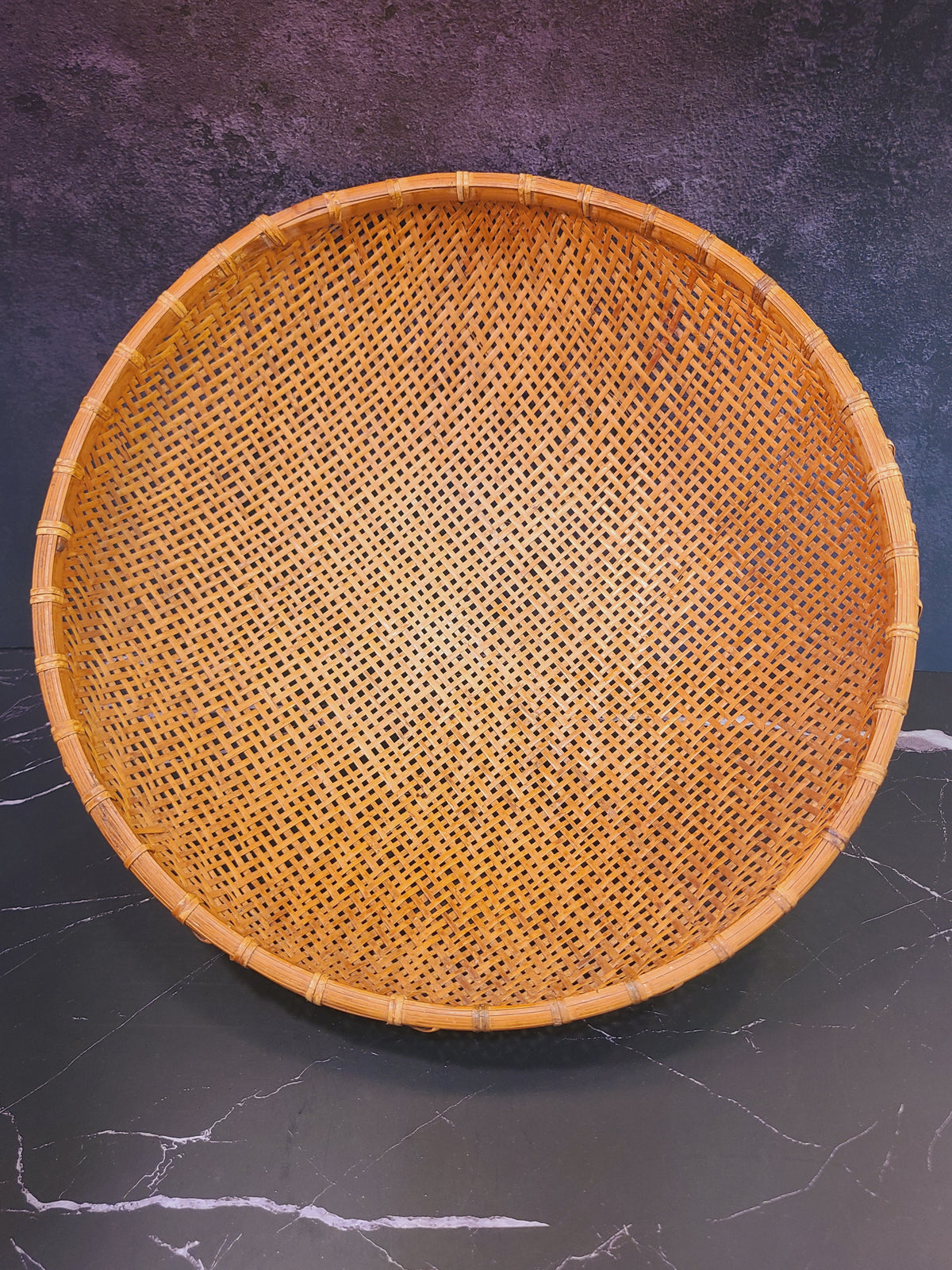 Overhead view of large round hand-woven bamboo winnowing basket on dark surface, 16.5 inch diameter, East Asian vintage folk art