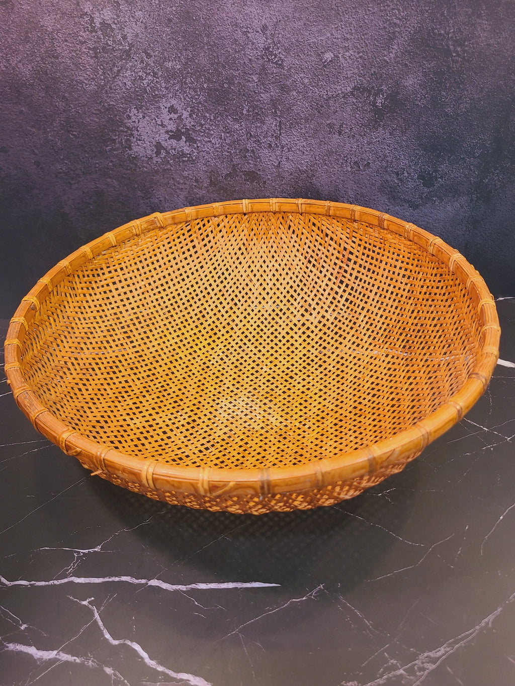Angled view of vintage East Asian bamboo winnowing basket showing deep bowl interior and rattan rim, coastal boho home decor accent