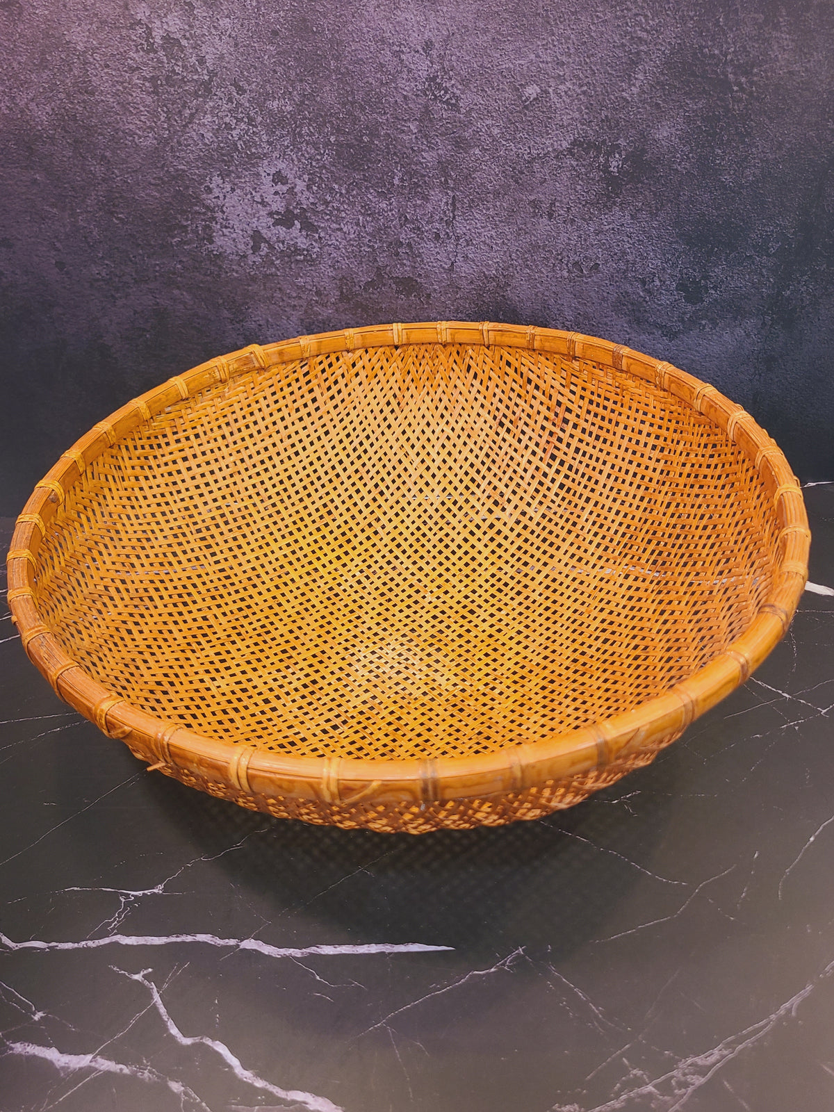Angled view of vintage East Asian bamboo winnowing basket showing deep bowl interior and rattan rim, coastal boho home decor accent