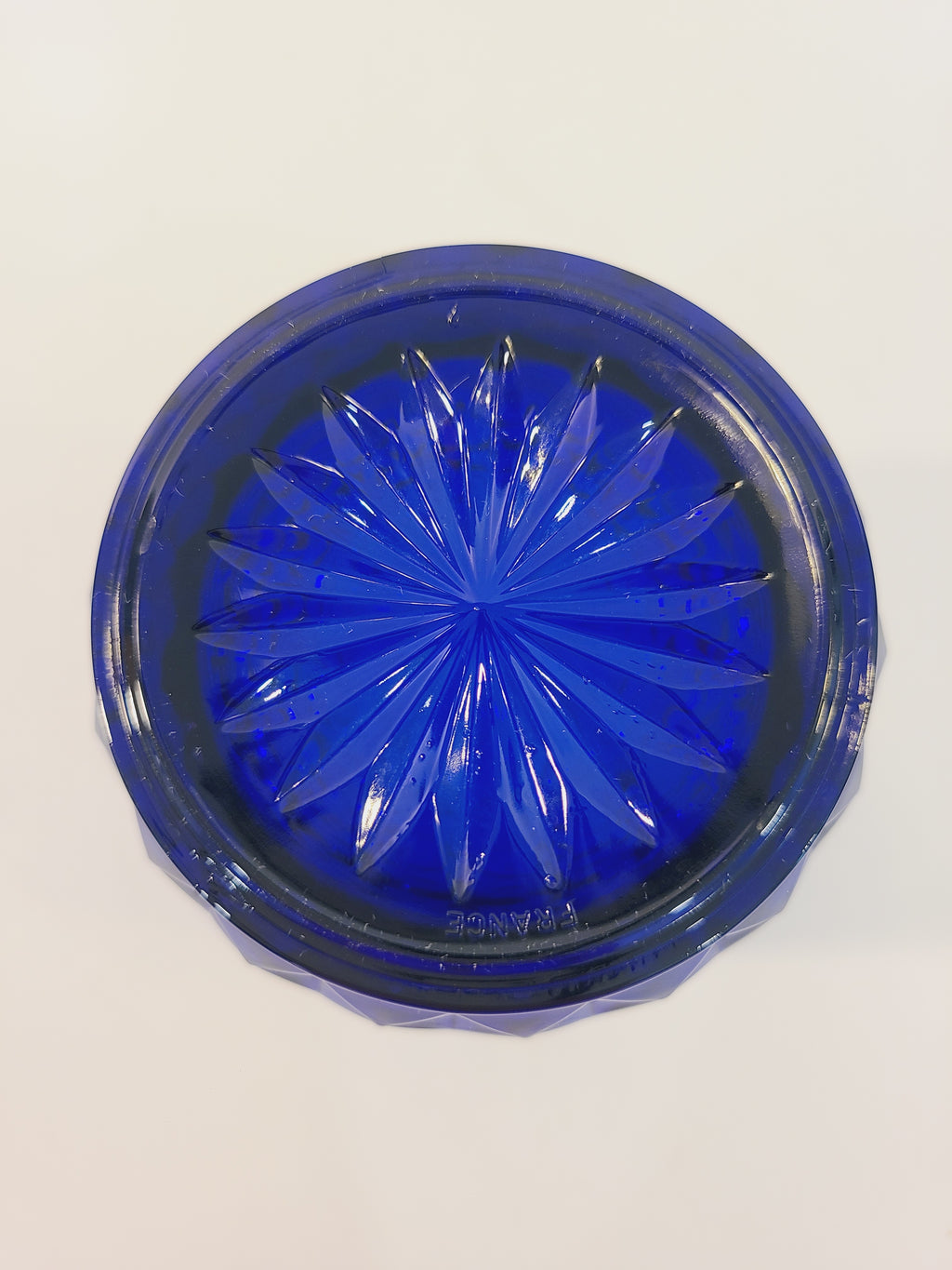 Bottom of Avon Royal Sapphire cobalt blue highball glass base showing starburst motif and France maker's mark — vintage Arcoroc
