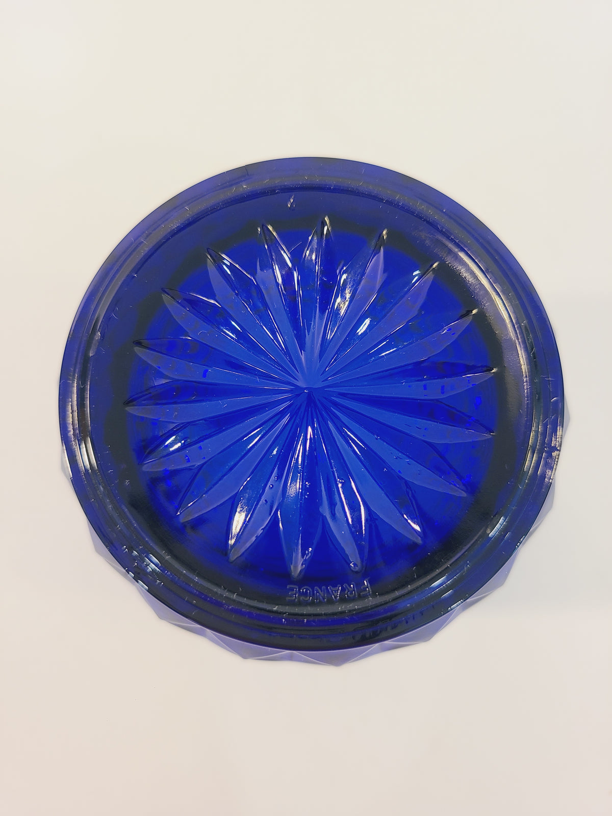 Bottom of Avon Royal Sapphire cobalt blue highball glass base showing starburst motif and France maker's mark — vintage Arcoroc
