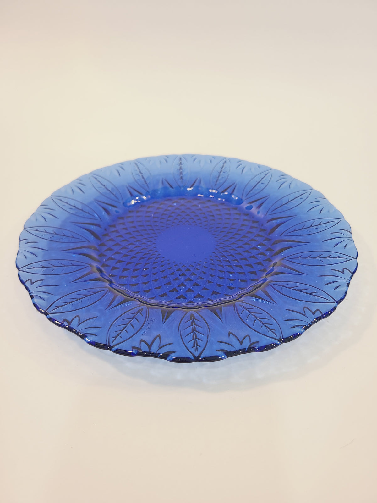Avon Royal Sapphire cobalt blue glass salad plate, angled view showing embossed leaf rim and diamond-optic texture — France