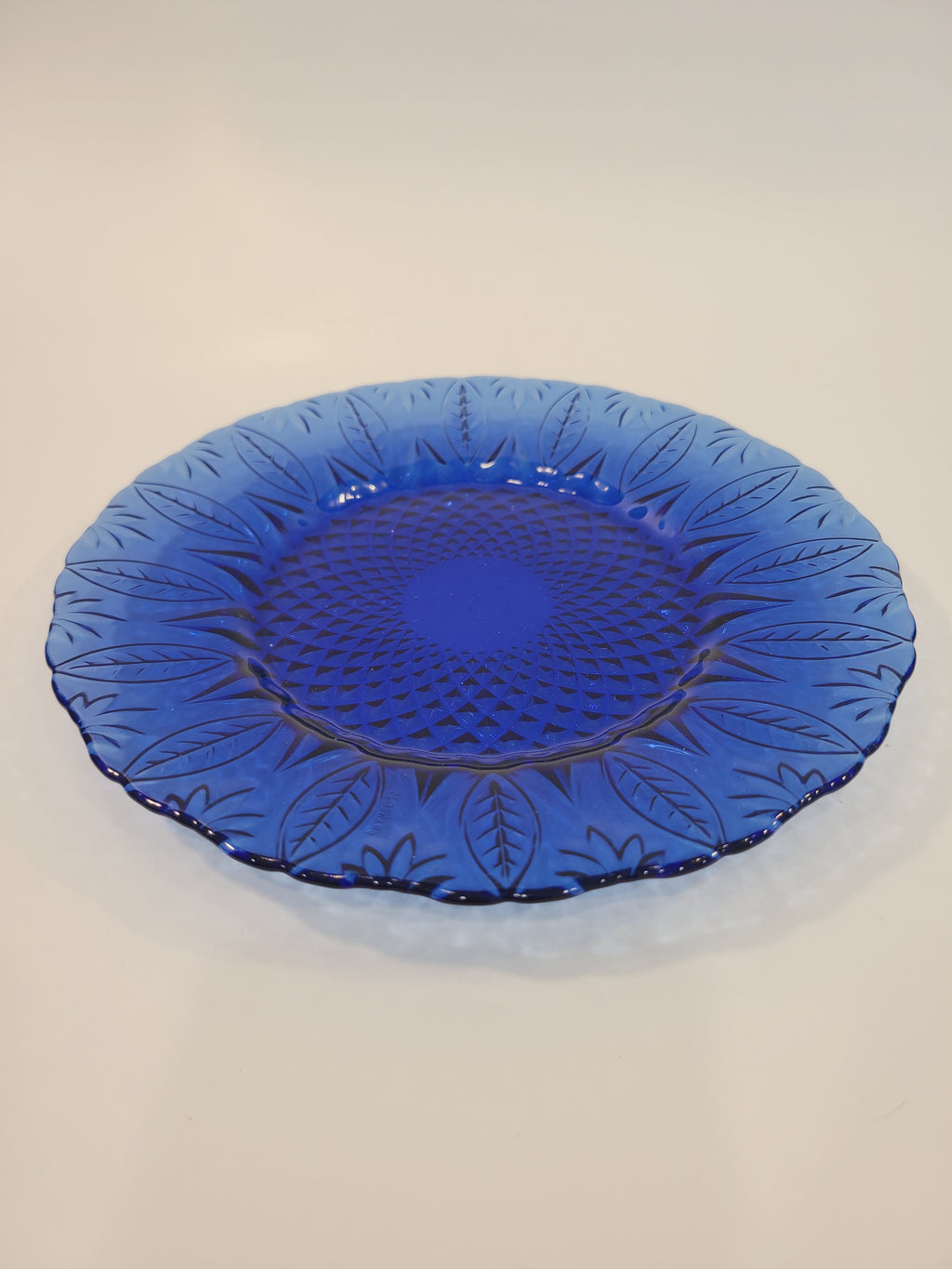 Avon Royal Sapphire cobalt blue glass dessert plate, side-angle view showing scalloped rim and embossed leaf pattern — France