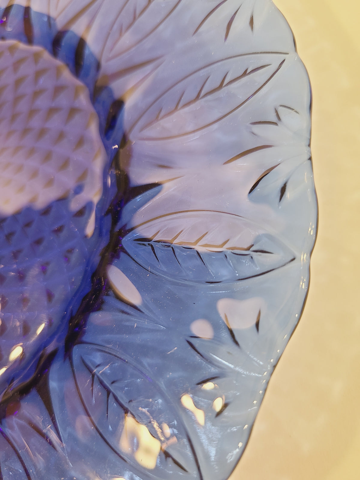 Macro close-up of embossed leaf rim on Avon Royal Sapphire cobalt blue glass plate showing light refraction — vintage France