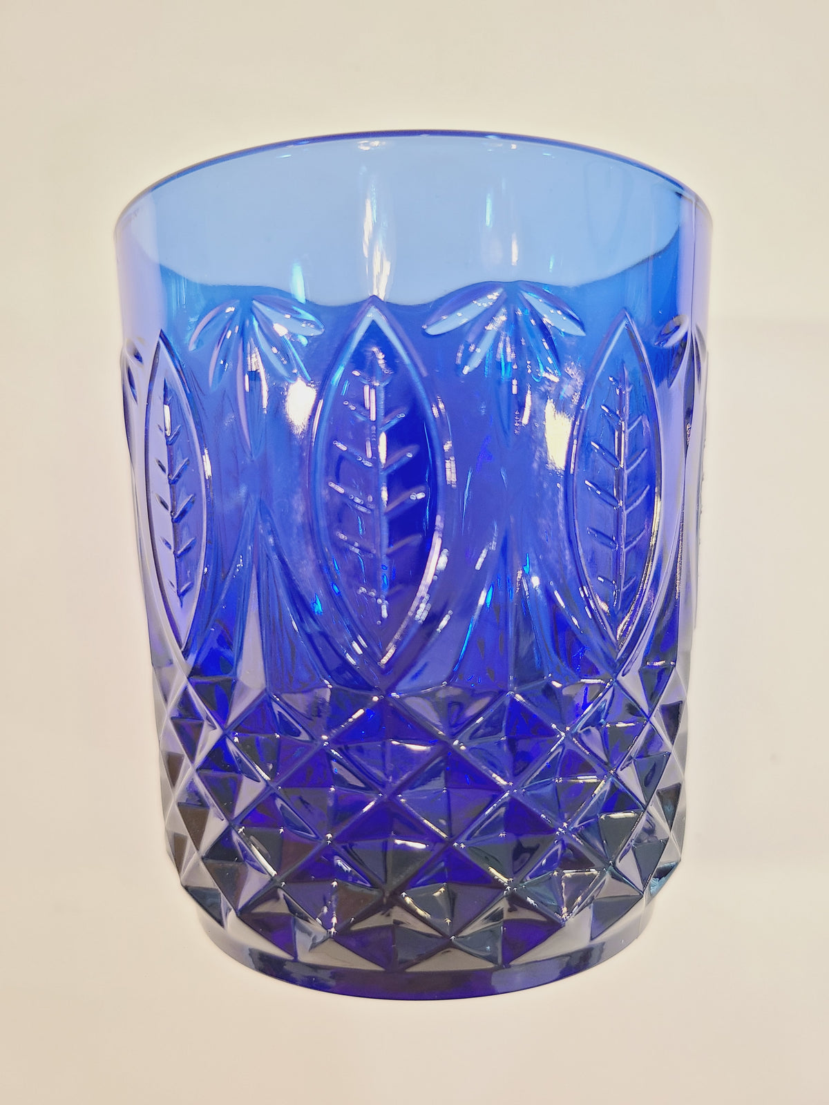 Close-up of embossed leaf and diamond-optic texture on Avon Royal Sapphire cobalt blue rocks glass — vintage France