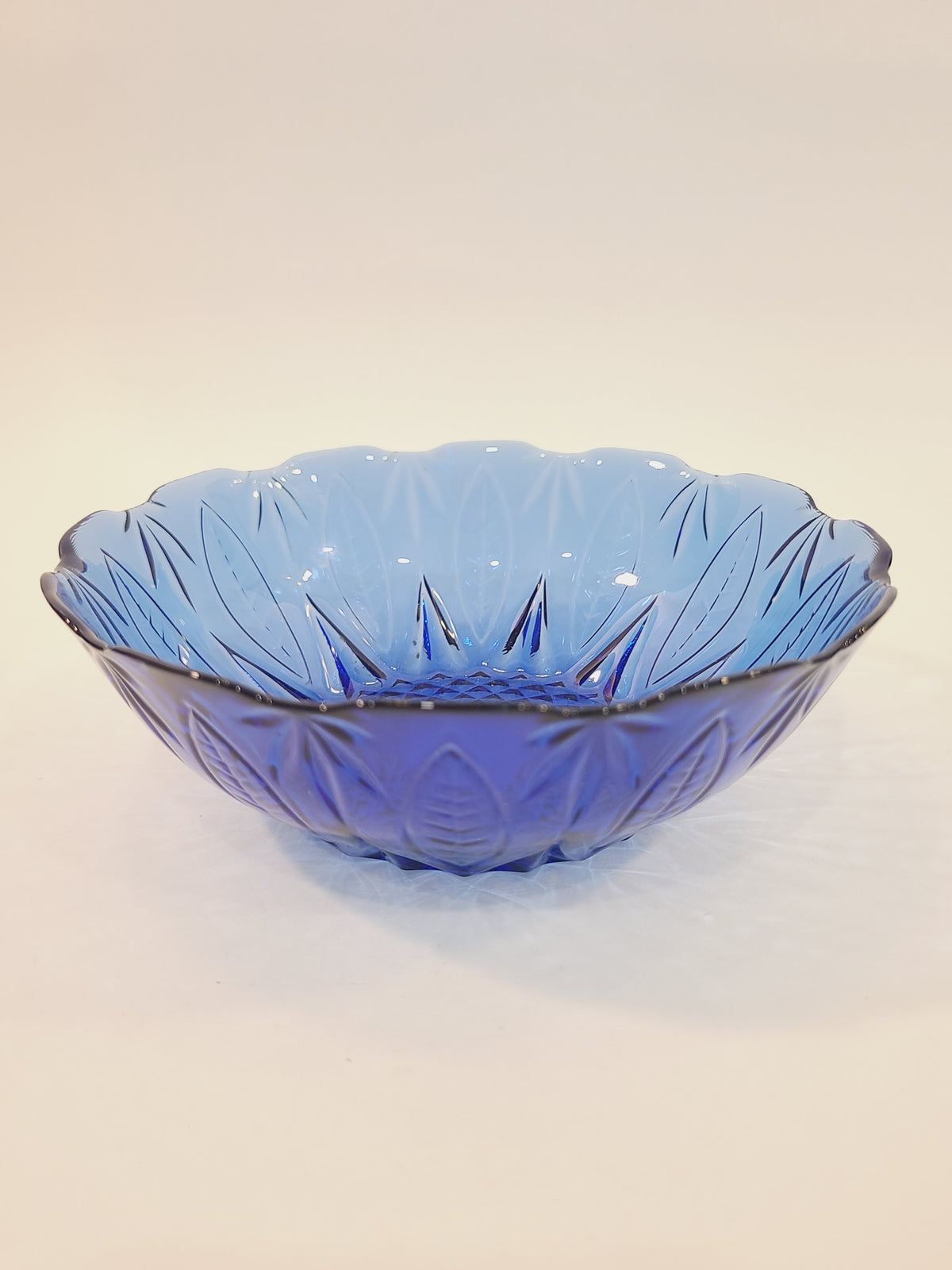 Avon Royal Sapphire cobalt blue glass cereal bowl, side-angle view showing scalloped rim and embossed leaf pattern — vintage France