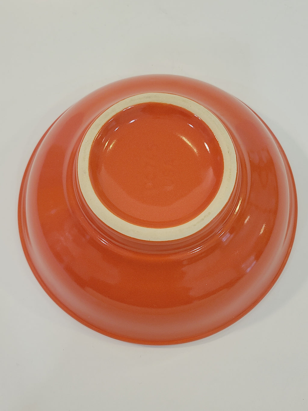 Base of mid-century American coral glaze utility bowl showing unglazed foot ring — USA stamped 1940s–1950s stoneware
