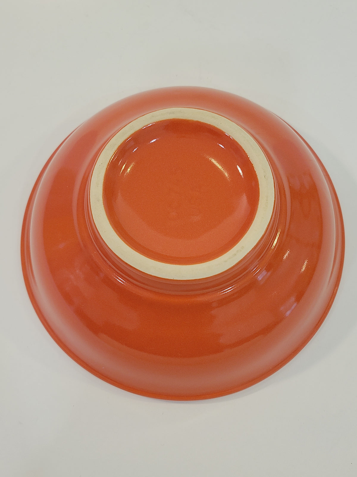 Base of mid-century American coral glaze utility bowl showing unglazed foot ring — USA stamped 1940s–1950s stoneware
