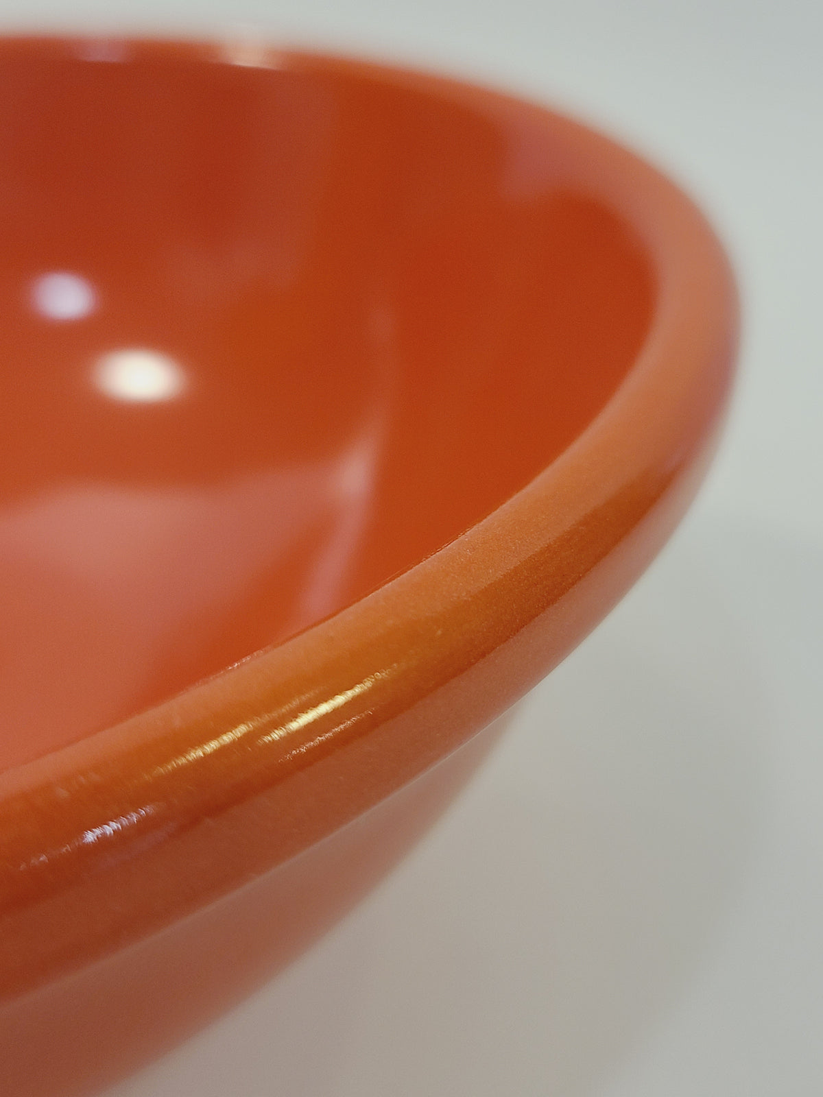 Close-up of rolled rim and high-gloss coral glaze interior on mid-century American utility bowl — vintage USA ceramic